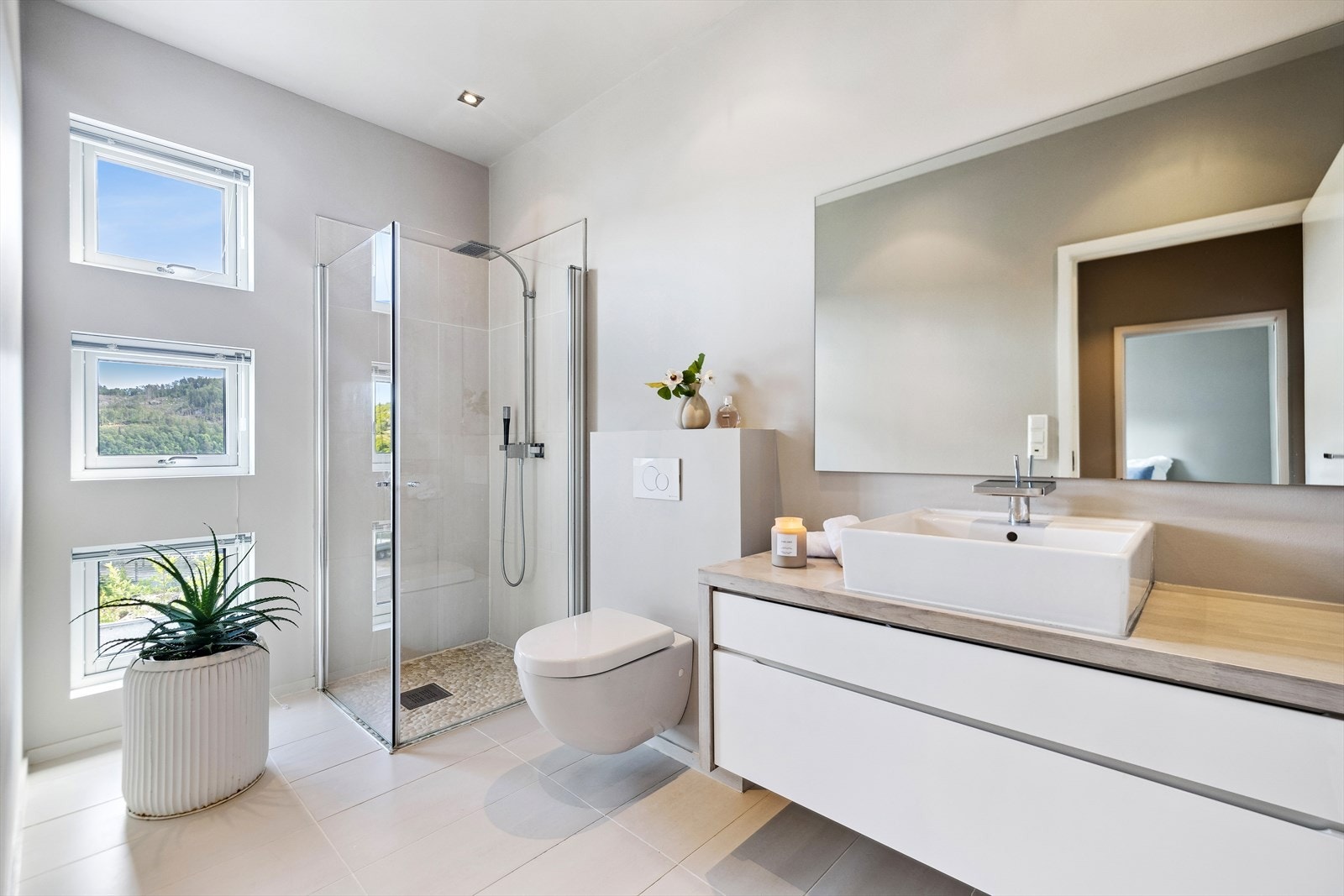 Moderne bad med stilrent design og godt lysinnslipp, perfekt for en avslappende start på dagen. Kvik baderomsinnreding, vegghengt toalett og dusjløsning med natursteinsgulv. Galleribilde