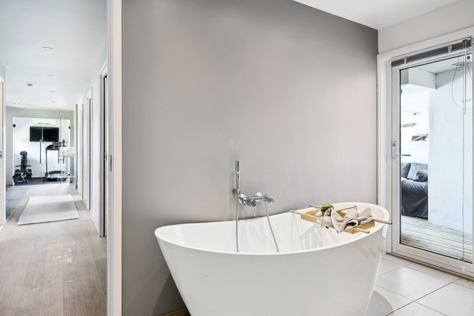 Elegant frittstående badekar på badet som har utgang til overbygd terrasse og videre ut til badebassenget. Galleribilde