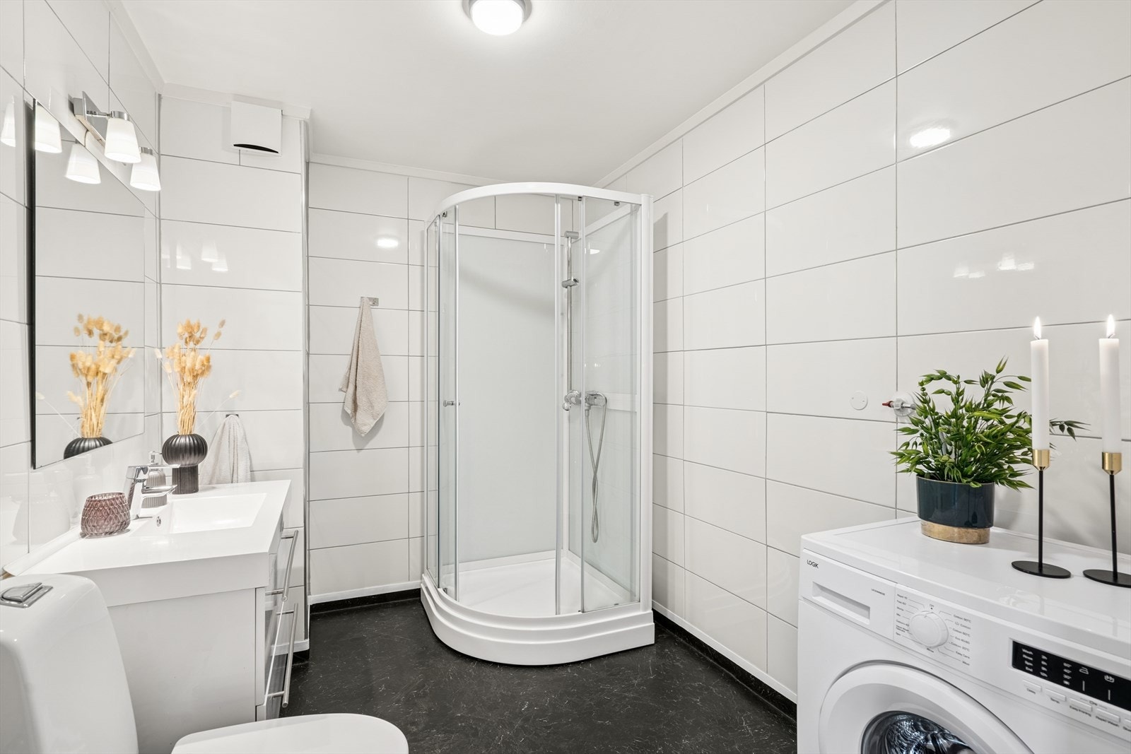 Baderommet er innredet med dusjkabinett og gulvstående klosett fra 2022, og servant og opplegg for vaskemaskin. Galleribilde