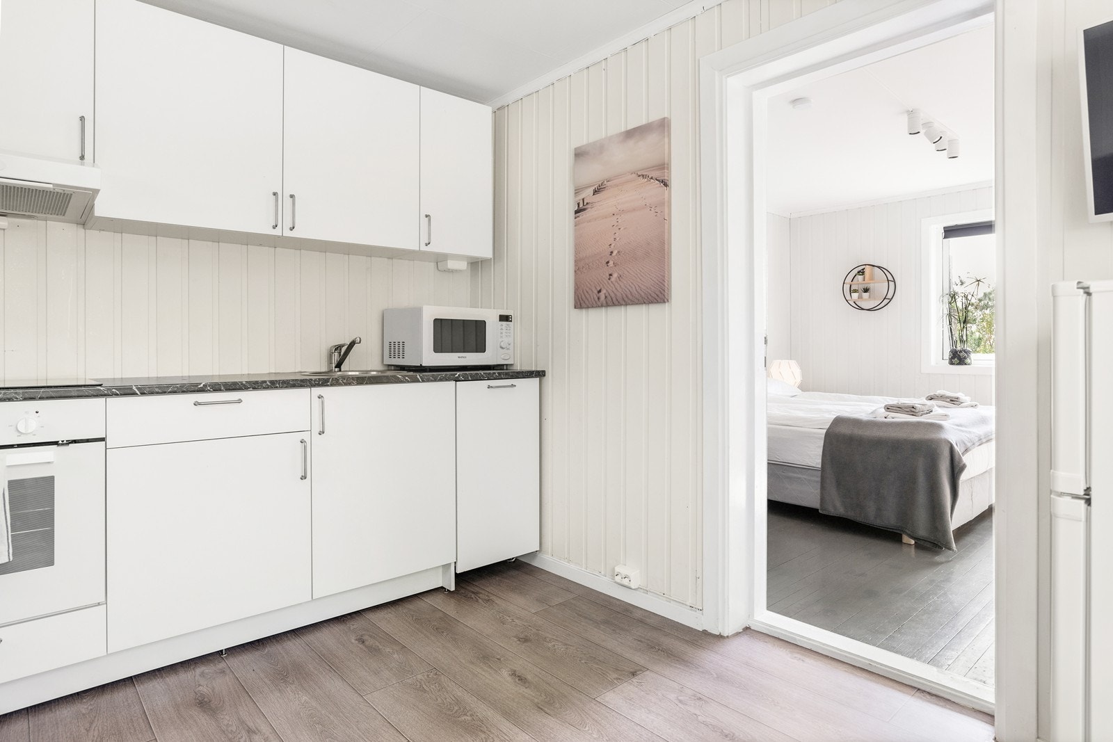 Kjøkkenet har hvite fronter og mørk benkeplate, samt integrert stekeovn, platetopp og ventilator. Galleribilde