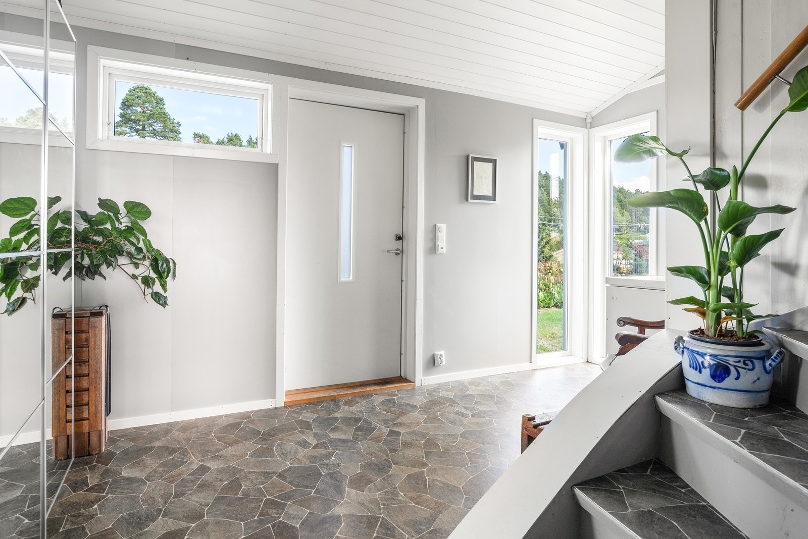 Entréen har belegg på gulv med varmekabler, malte vegger og malt panel i himlingen. Her finnes en praktisk skyvedørsgarderobe med speildører. Galleribilde