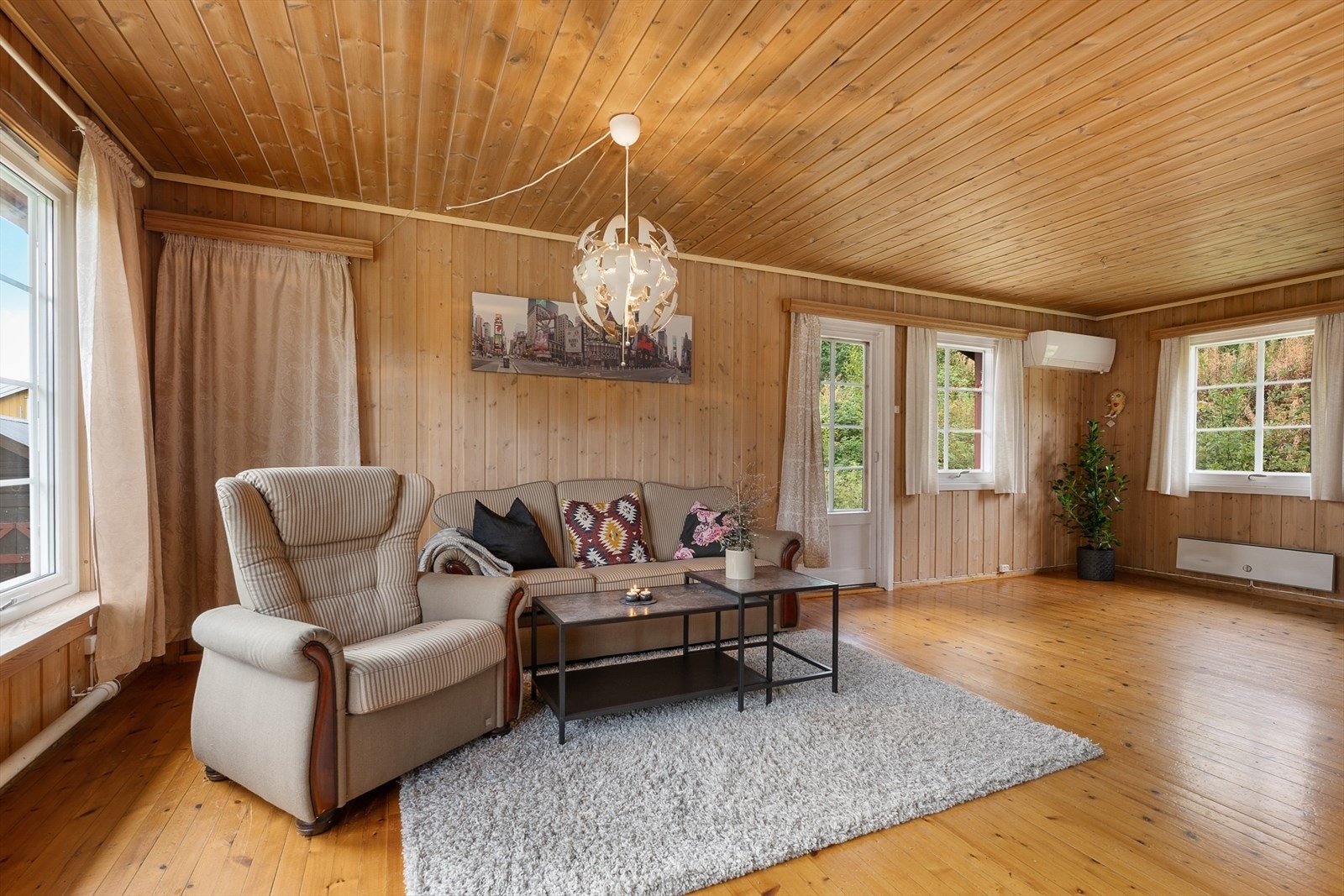 I stuen er det god plass for sofagruppe og annet etter ønske. Bak gardinen er det en dør og trapp ned til underetasjen. Galleribilde