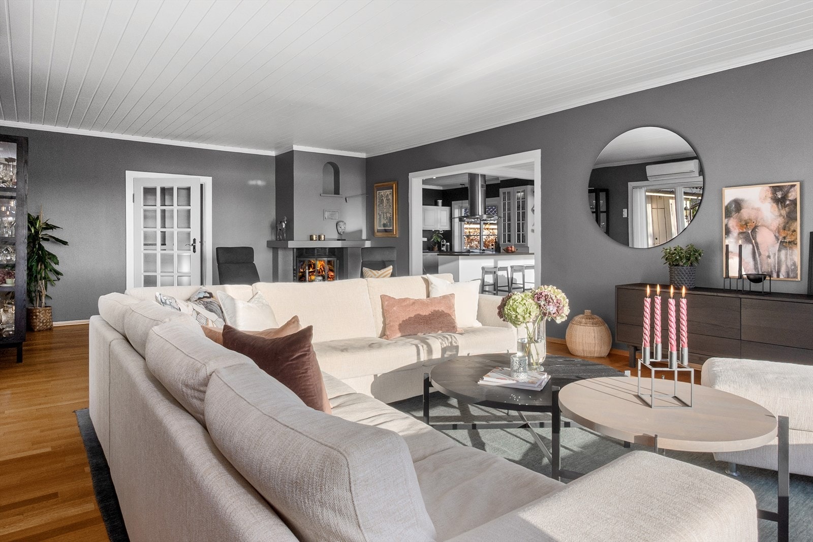 Stuen kan naturlig deles inn i soner med plass til en romslig sofagruppe og et hyggelig hjørne ved peisen, perfekt for å skape et sosialt miljø for både vertskap og gjester. Galleribilde