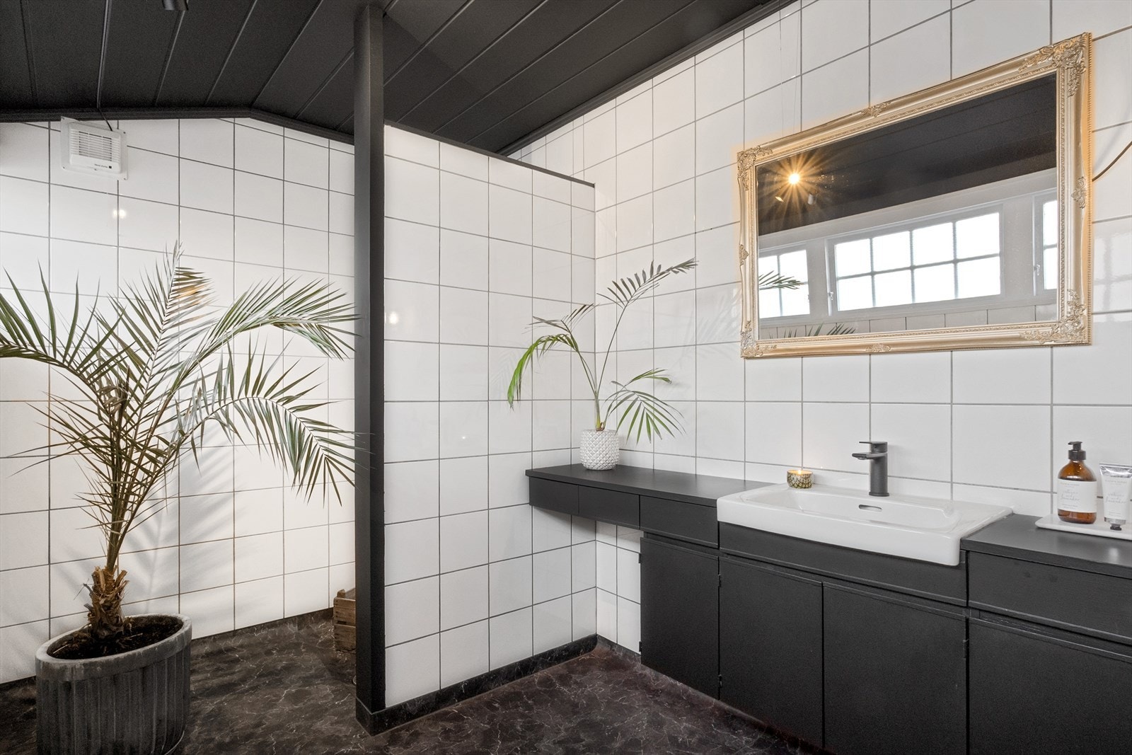I boligen er det to bad. Badet i 1. etasje har fått nytt linoleumsbelegg på gulv i 2020 og har mørke fronter, hvite fliser og sorte detaljer. Galleribilde