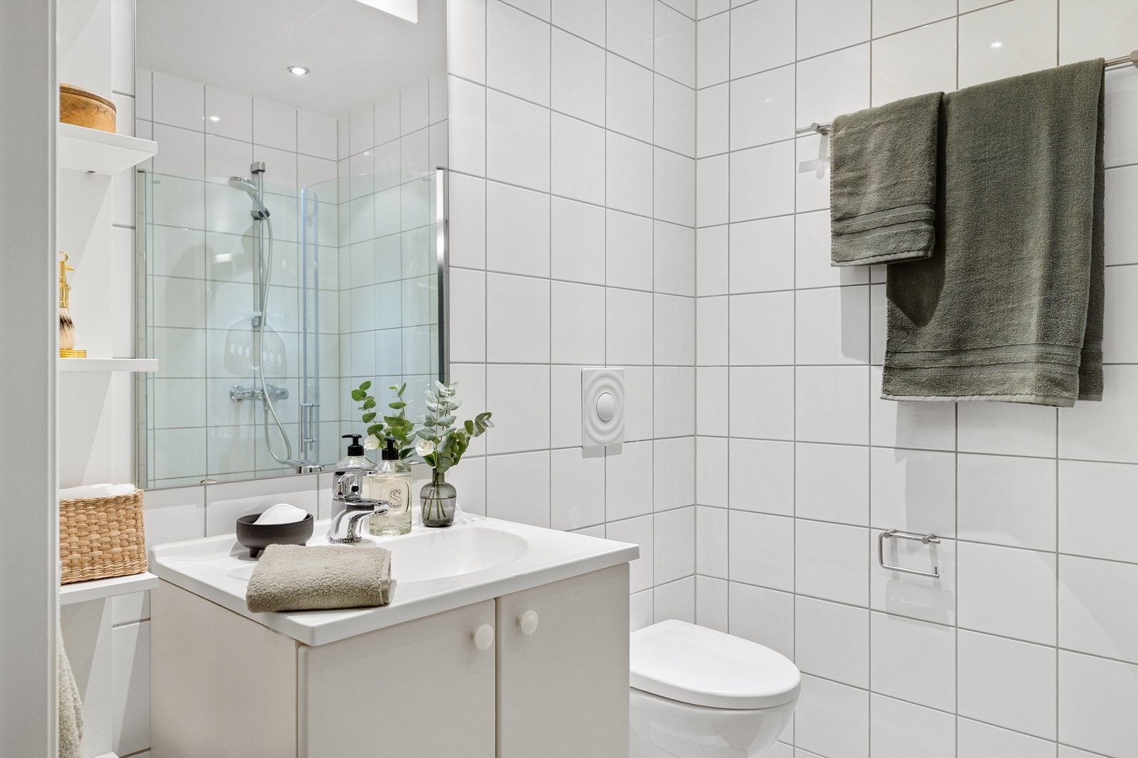 Pent flislagt baderom fra byggeårene med gulvvarme. Badet har veggmontert toalett og dusjhjørne med buede svingdører. Galleribilde