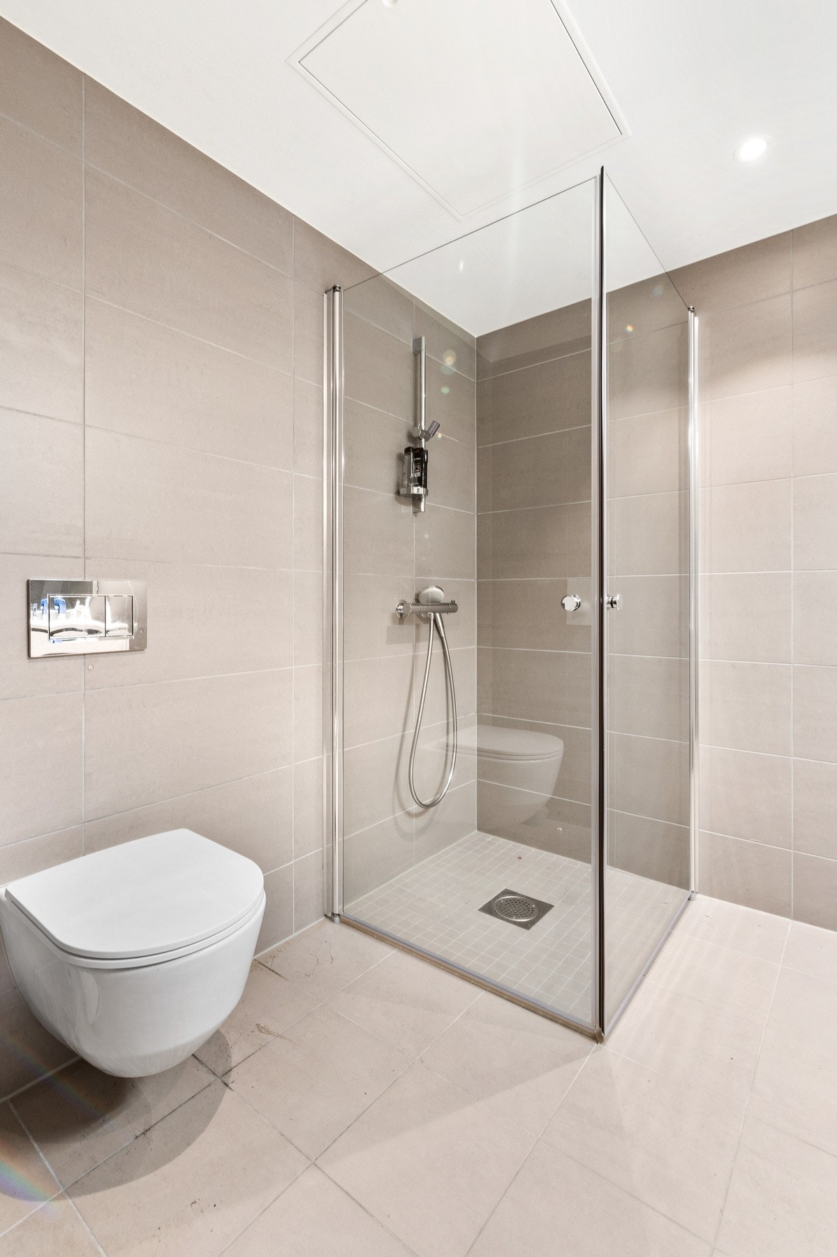 Et lunt badrom fra 2024 flislagte flater og downlights i taket. Galleribilde