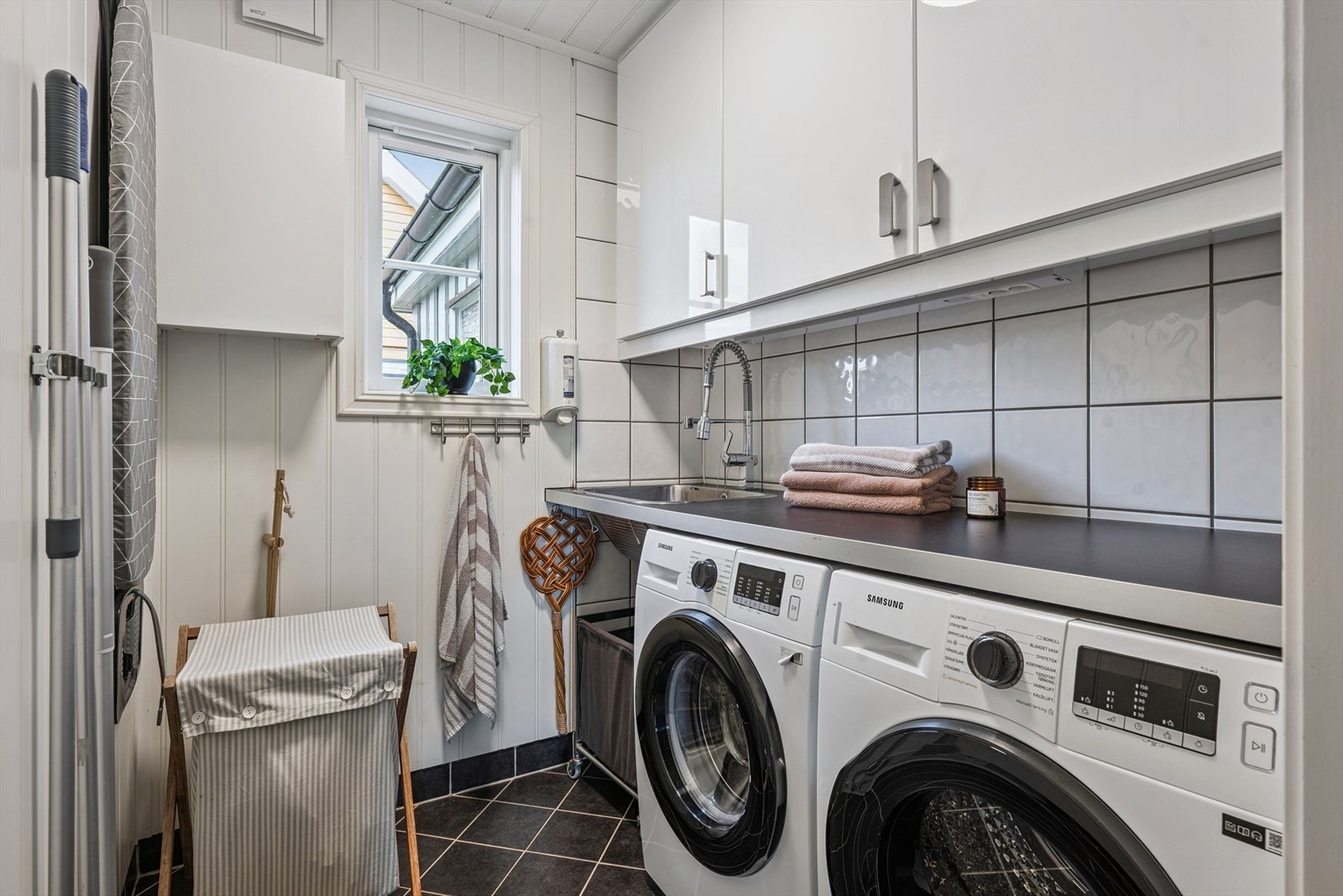 Lyst og pent vaskerom med opplegg for vaskemaskin, tørketrommel og utslagsvask. Galleribilde