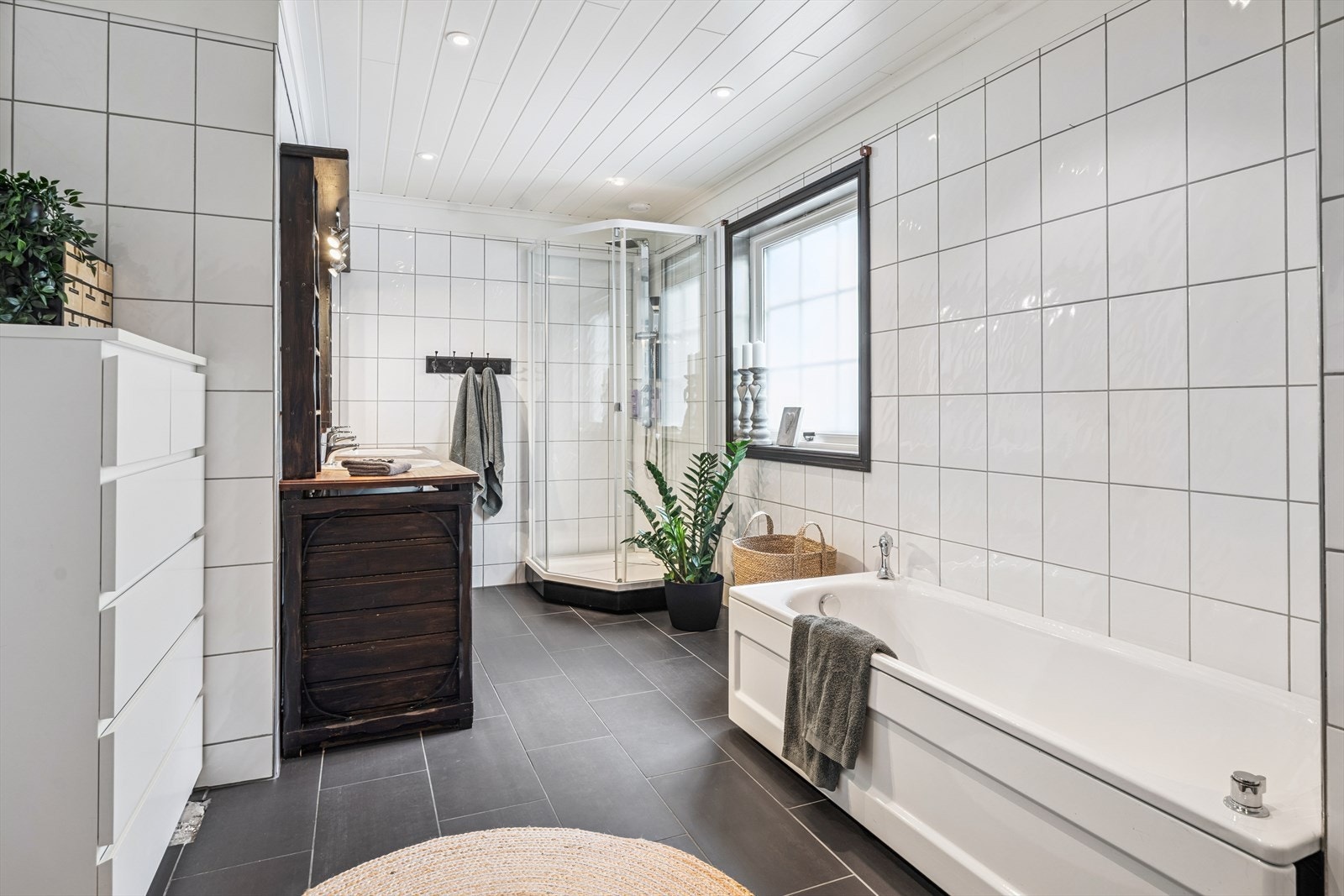 Stort flislagt og tidløst bad med dusjkabinett og badekar Galleribilde