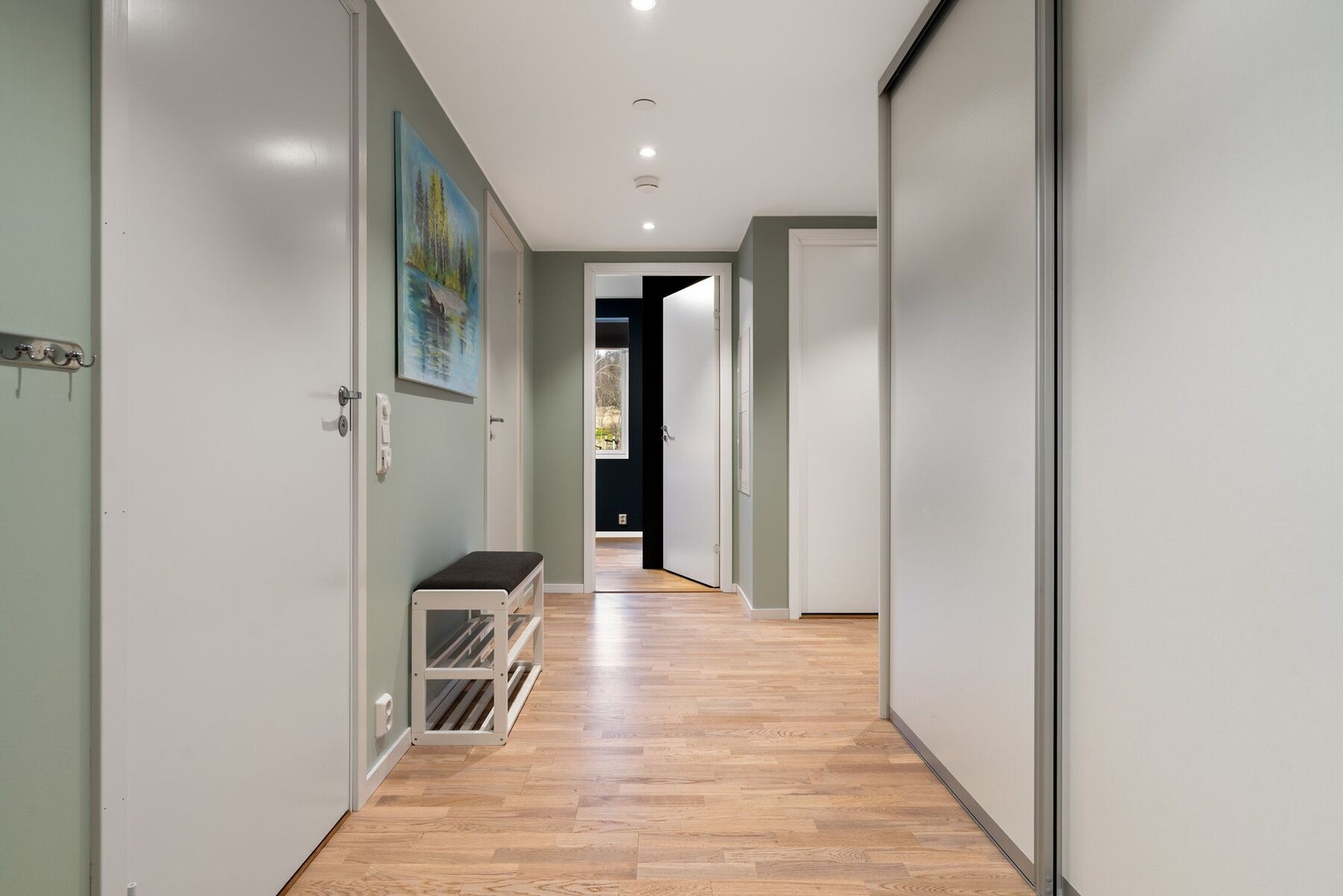 Lys og innbydende gang på 11,7 m² som gir et varmt førsteinntrykk med lyse flater, praktisk planløsning og plassbygd skyvedørsgarderobe fra Elfa. Galleribilde