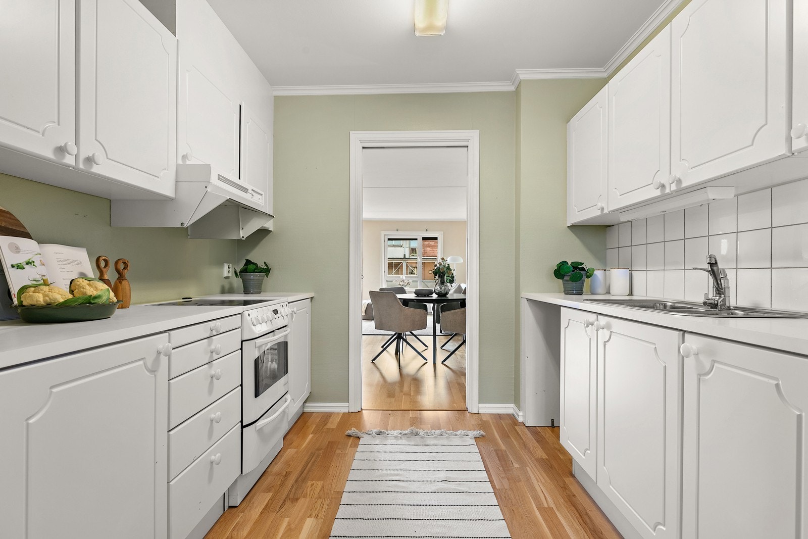 Kjøkkenet har en klassisk innredning med lyse, profilerte fronter og en benkeplate i laminat med nedfelt vask. Galleribilde