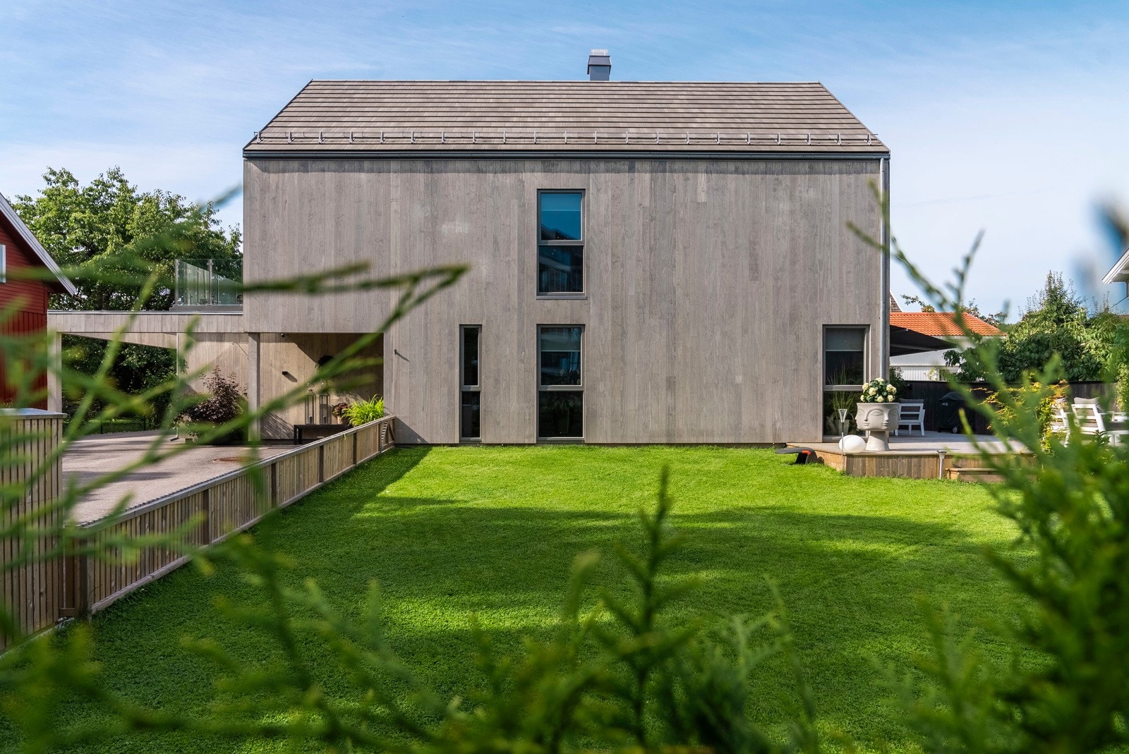 Eneboligen ligger på en solfylt og velstelt tomt, der en inngjerdet hage er pent opparbeidet med gressplen, trær, busker, hekk mot veien og diverse beplantning. Galleribilde