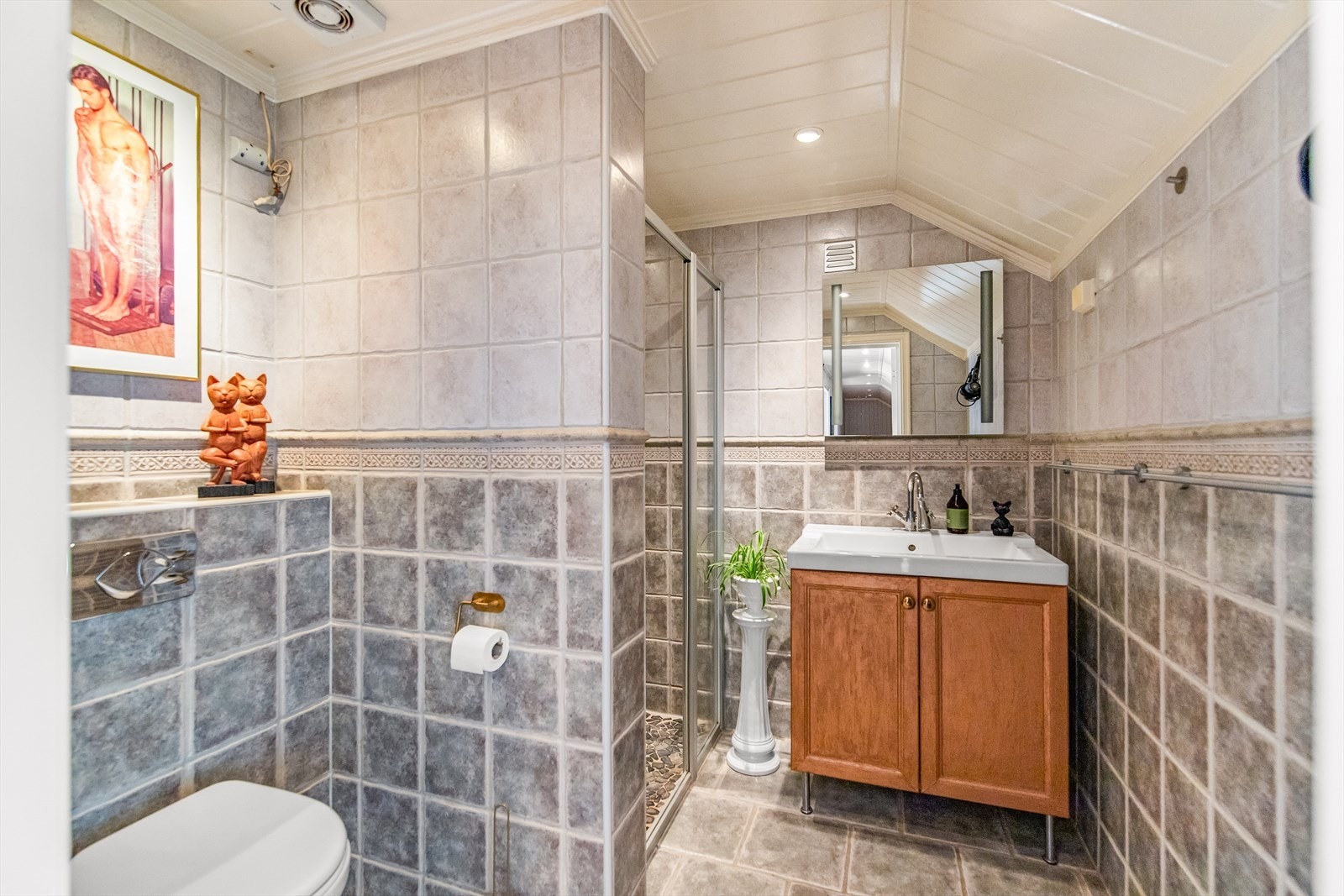 Bad fra ca. 2005 med flislagte overflater, servant, vegghengt toalett og dusj. Galleribilde