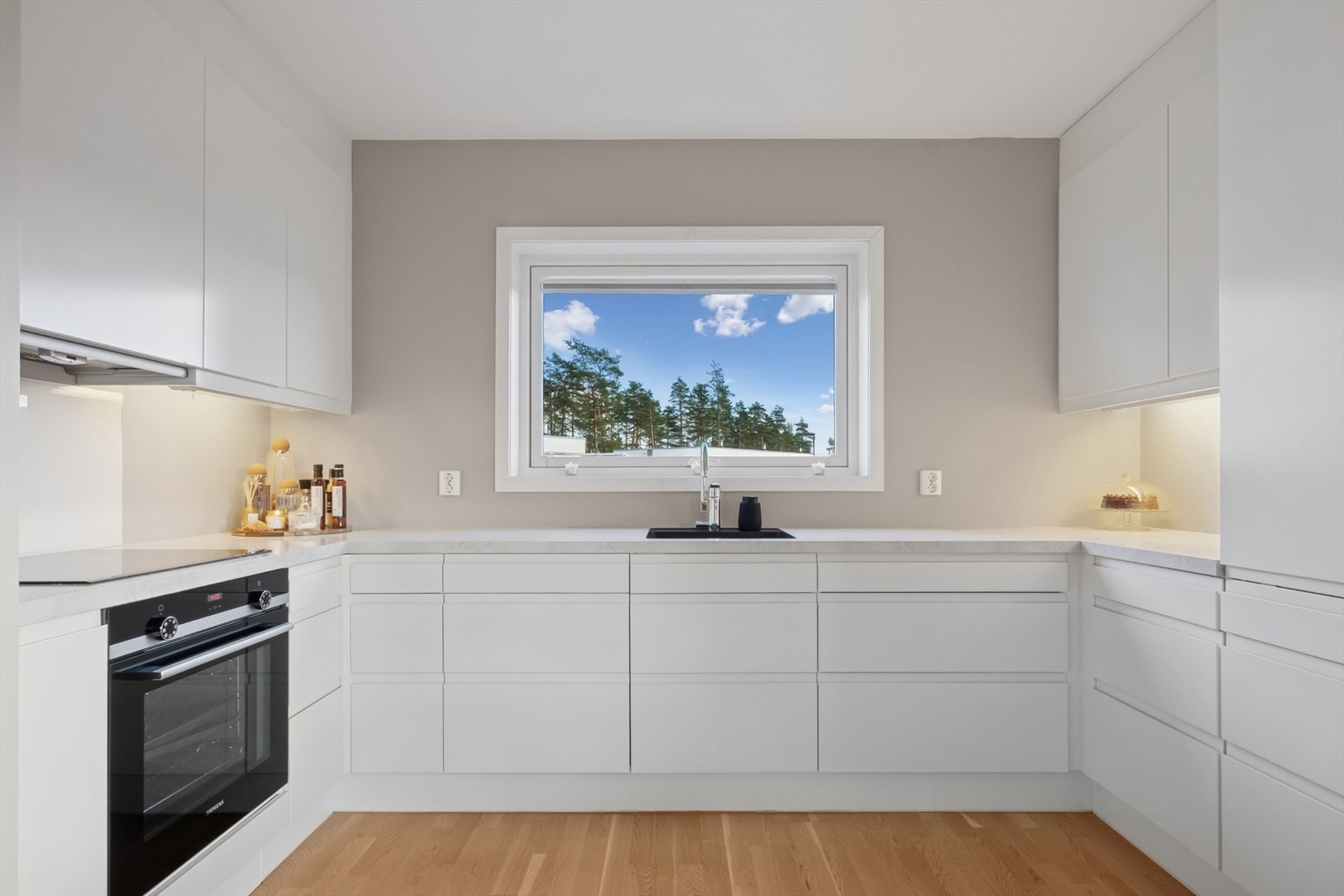 Kjøkkeninnredningen er moderne, med hvite, glatte fronter og laminert benkeplate med underlimt vask i kompositt. Galleribilde