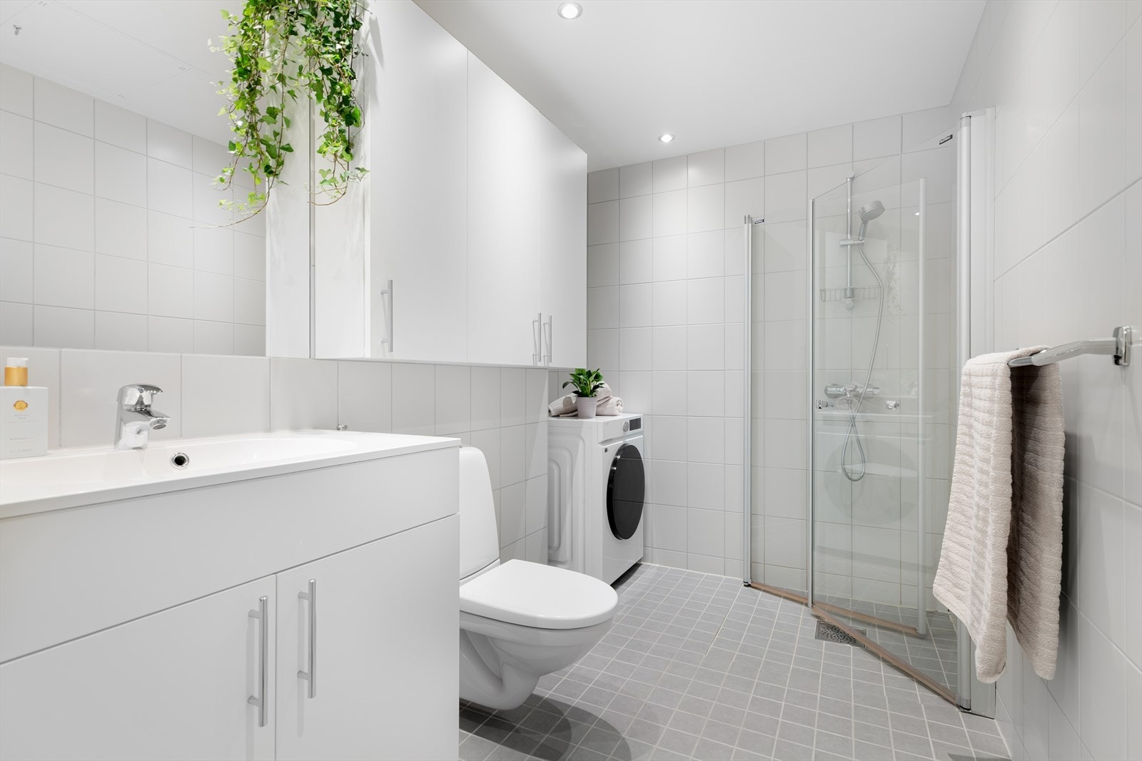 Badet er helfliset og utstyrt med vegghengt toalett, servantinnredning og dusjhjørne. Galleribilde