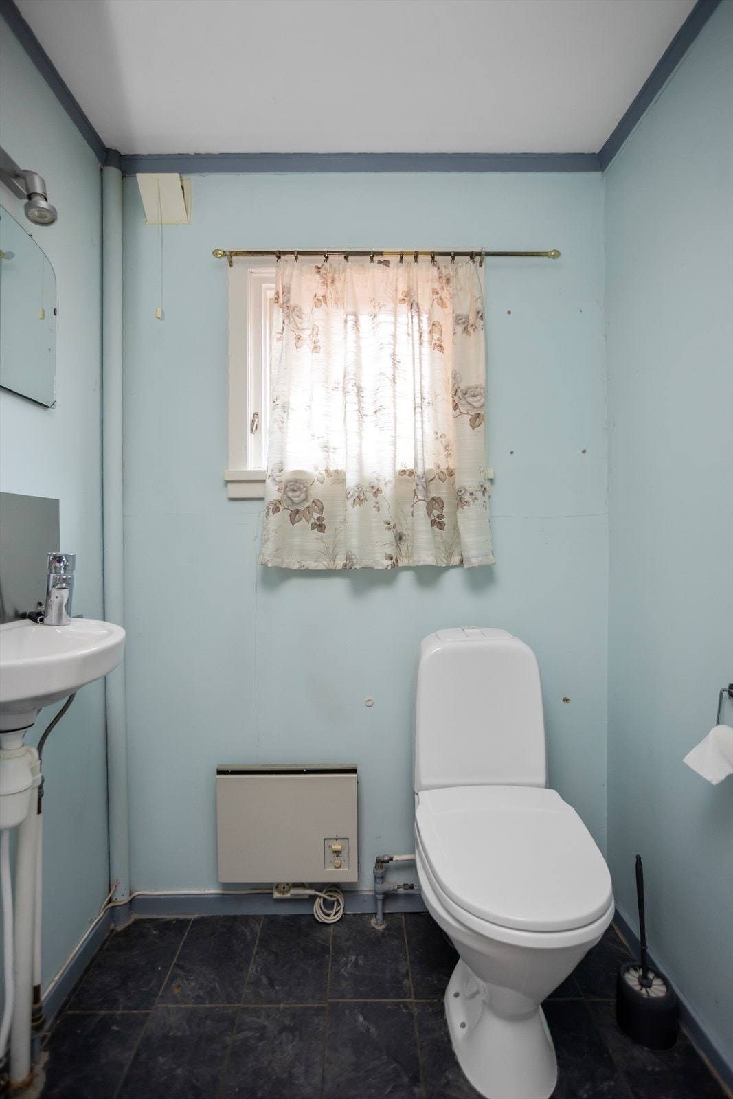 Toalettrommet ligger i tilknytning til entreèn med et mindre vindu, trukket godt opp på innerveggen. Toalettrommet er innredet med sokkeltoalett og veggmontert håndvask/servant. Galleribilde