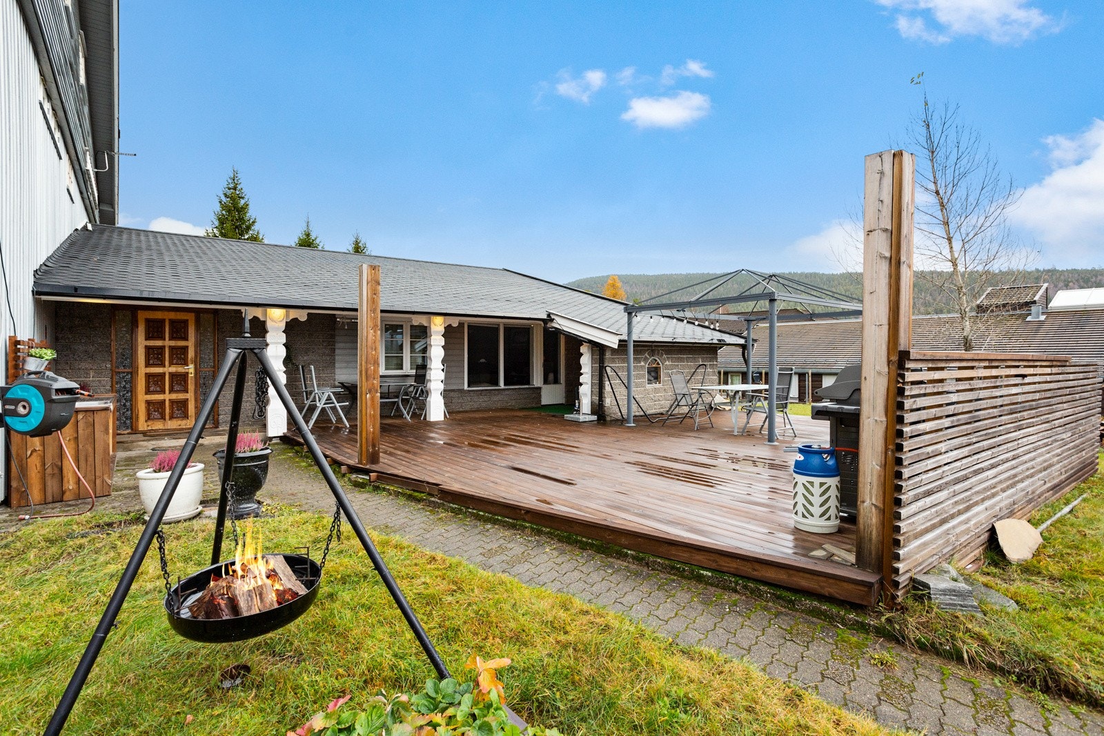 Terrassplatting og adkomst til romslig hage, som ligger skjermet fra veien på baksiden av bygget. Galleribilde