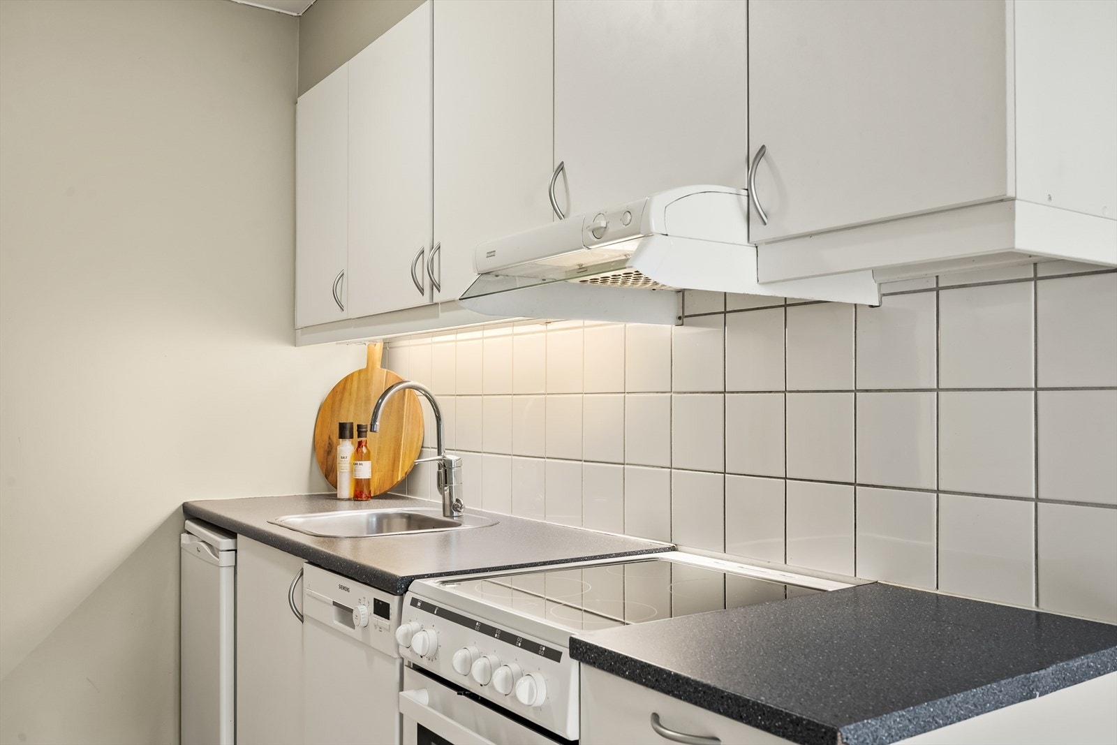 Innredningen har hviter glatte fronter og benkeplate av laminat, ny ovn fra 2025 Galleribilde