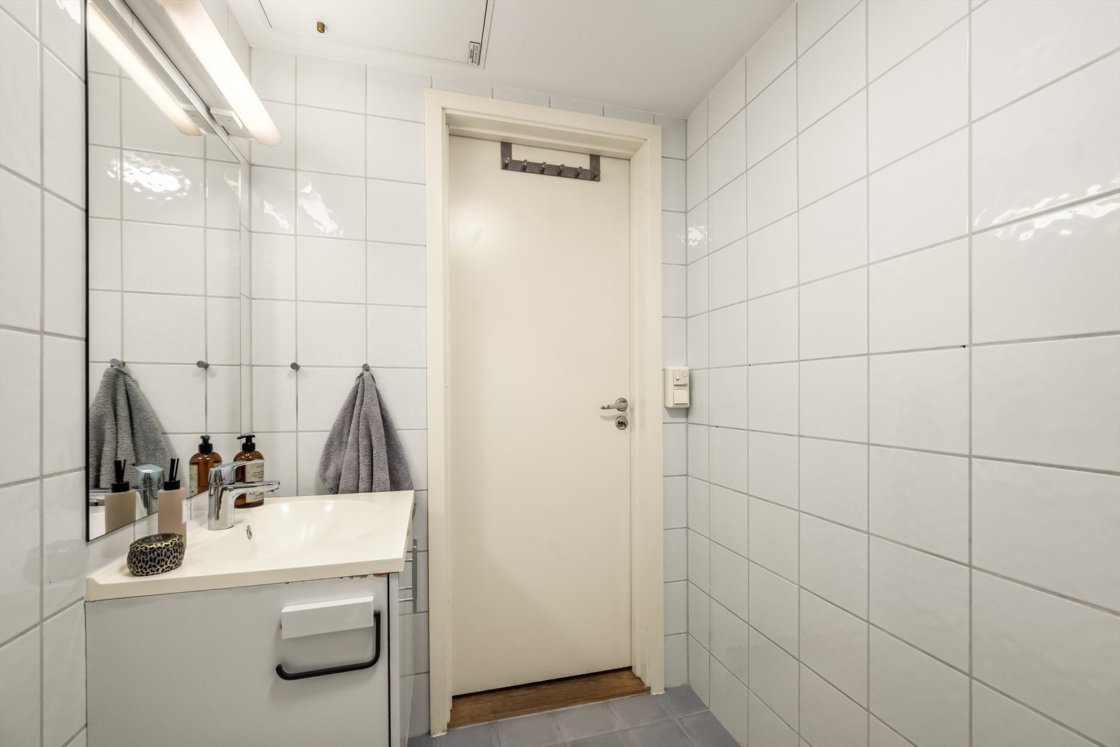 Badet er innredet med dusjhjørne, opplegg for vaskemaskin, heldekkende servant, hvitt servantskap, speil og veggmontert toalett Galleribilde