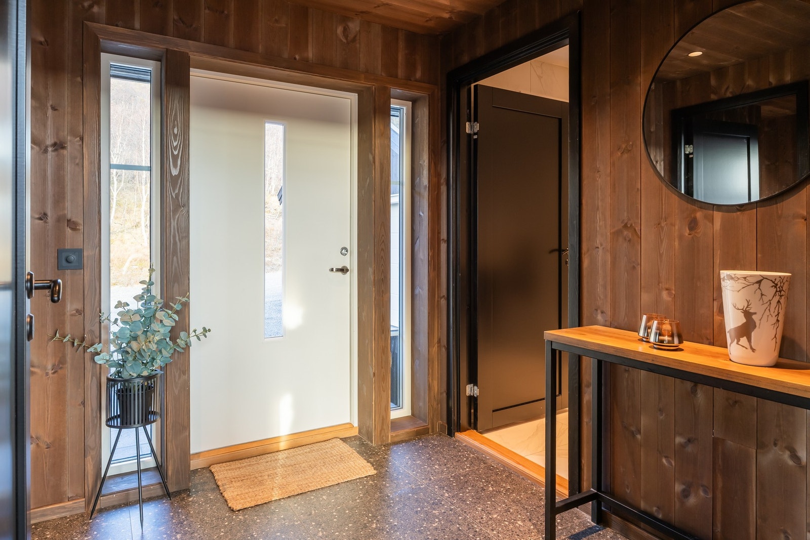 Entréen har en stilren og innbydende utførelse med flislagt gulv.