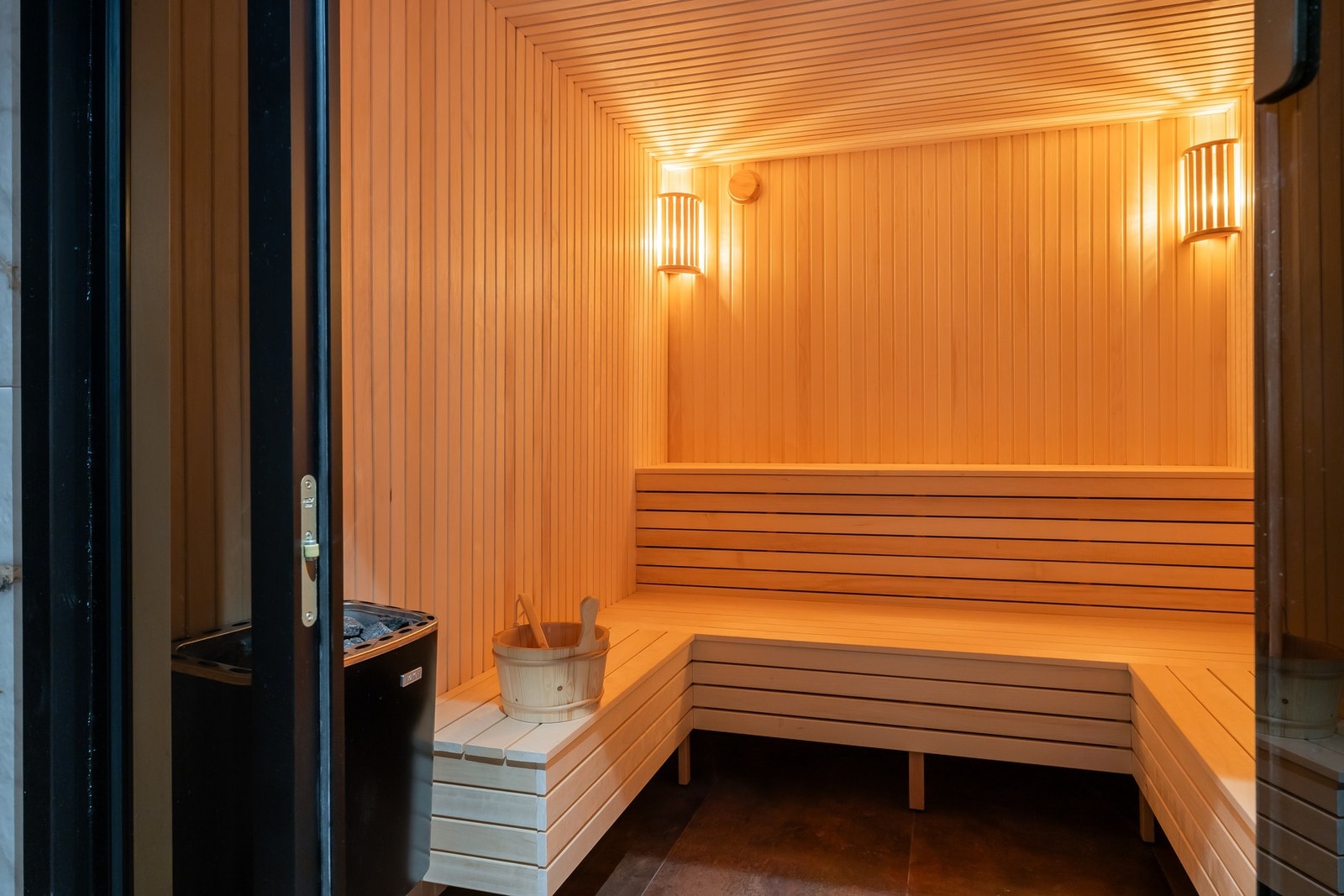 Badstu har fliser på gulv samt plassbygde sittebenker og badstuovn.