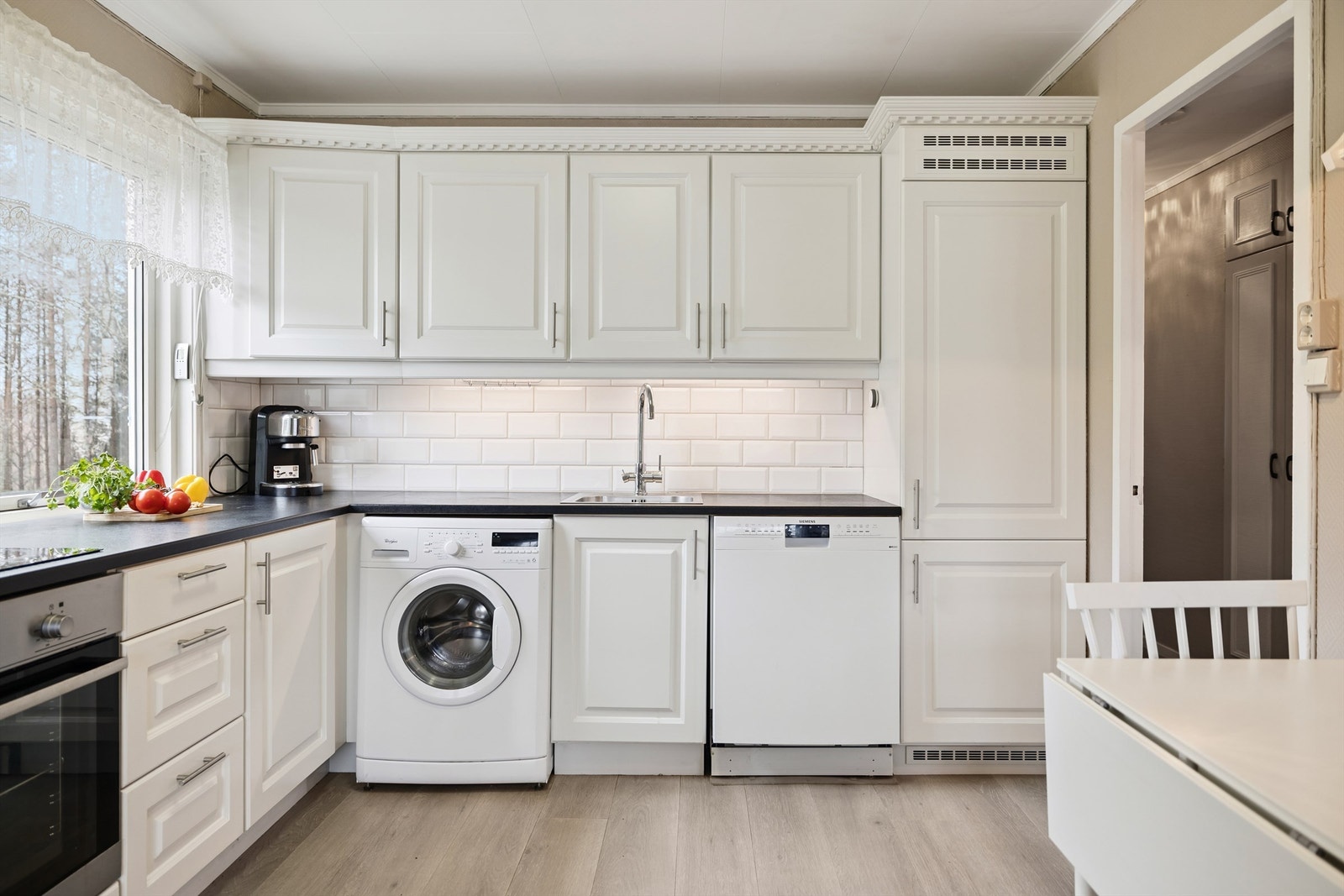 Innredningen har integrert stekeovn, platetopp og opplegg for vaskemaskin. Lekre fliser mellom benk og overskap. Galleribilde