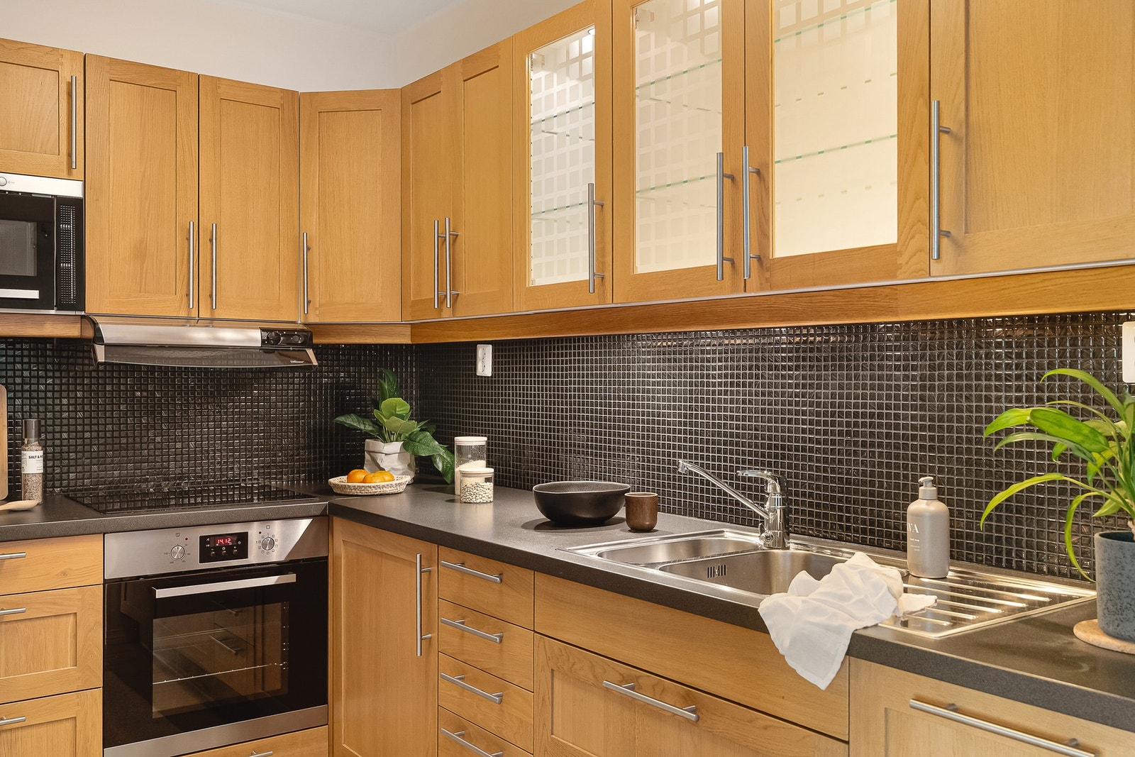 Kjøkkeninnredningen består av profilerte fronter, to av overskapene har glassfronter, laminat benkeplate, over benkeplaten er det benyttet fliser, stål oppvaskkum og ventilator. Galleribilde