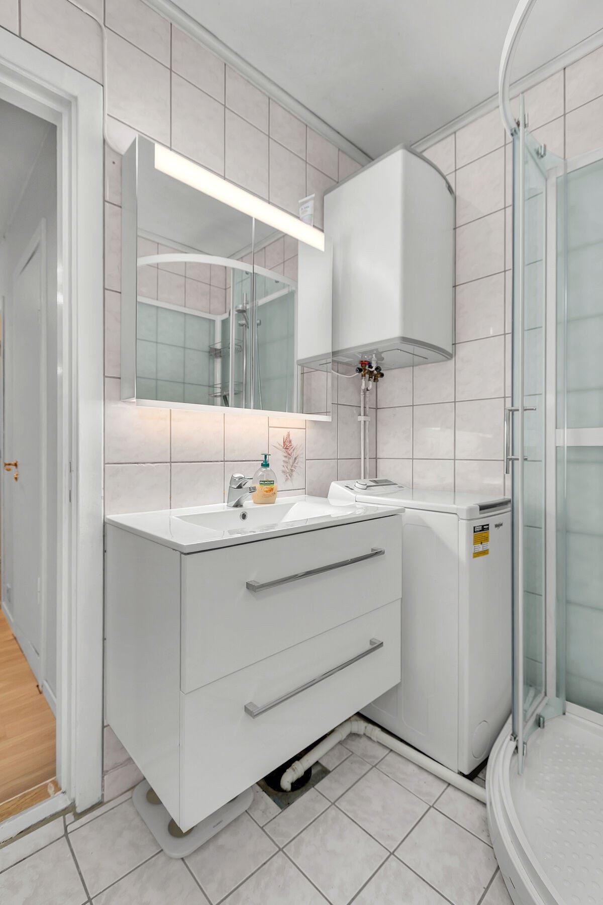 Bad med fliser på gulv og dusjkabinett. Vaskemaskin på badet følger med salget. Galleribilde