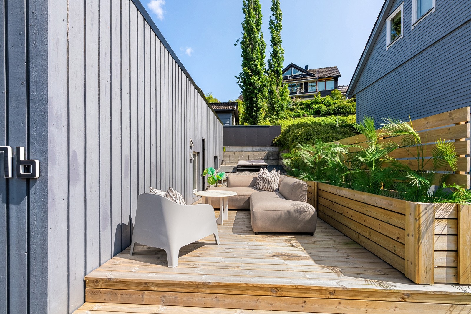 Lun og skjermet terrasse med beplantet bed. Galleribilde