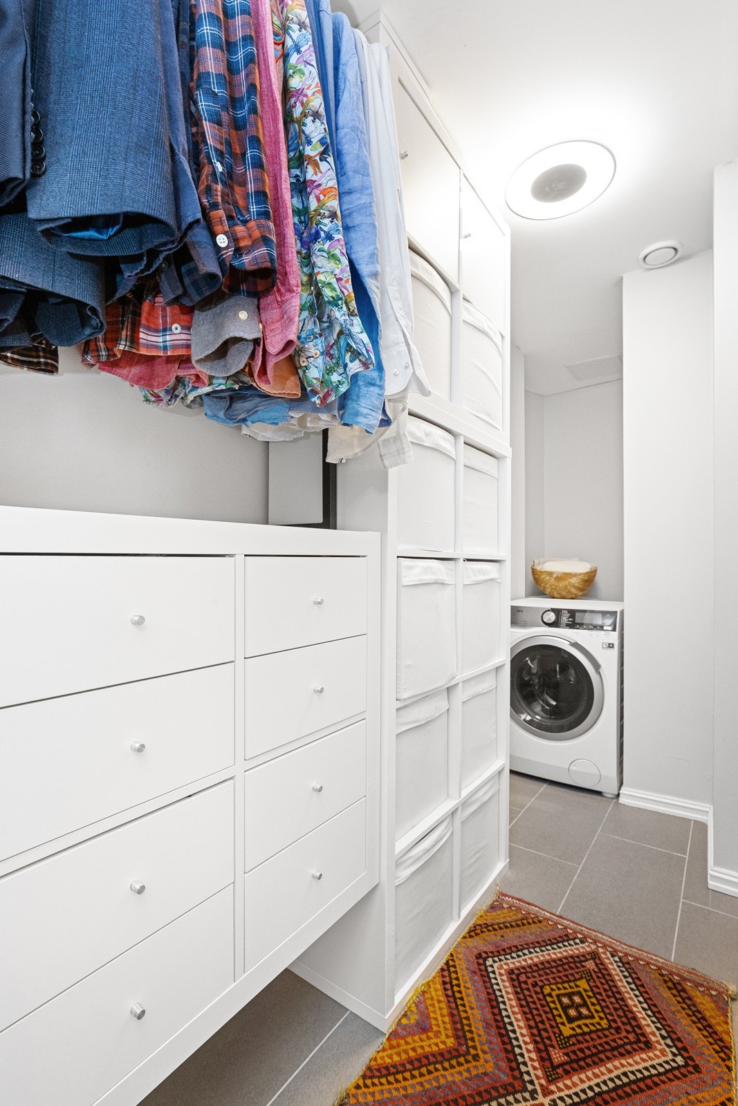 Bod med fliser på gulv og innredet som garderoberom med opplegg for vaskemaskin Galleribilde