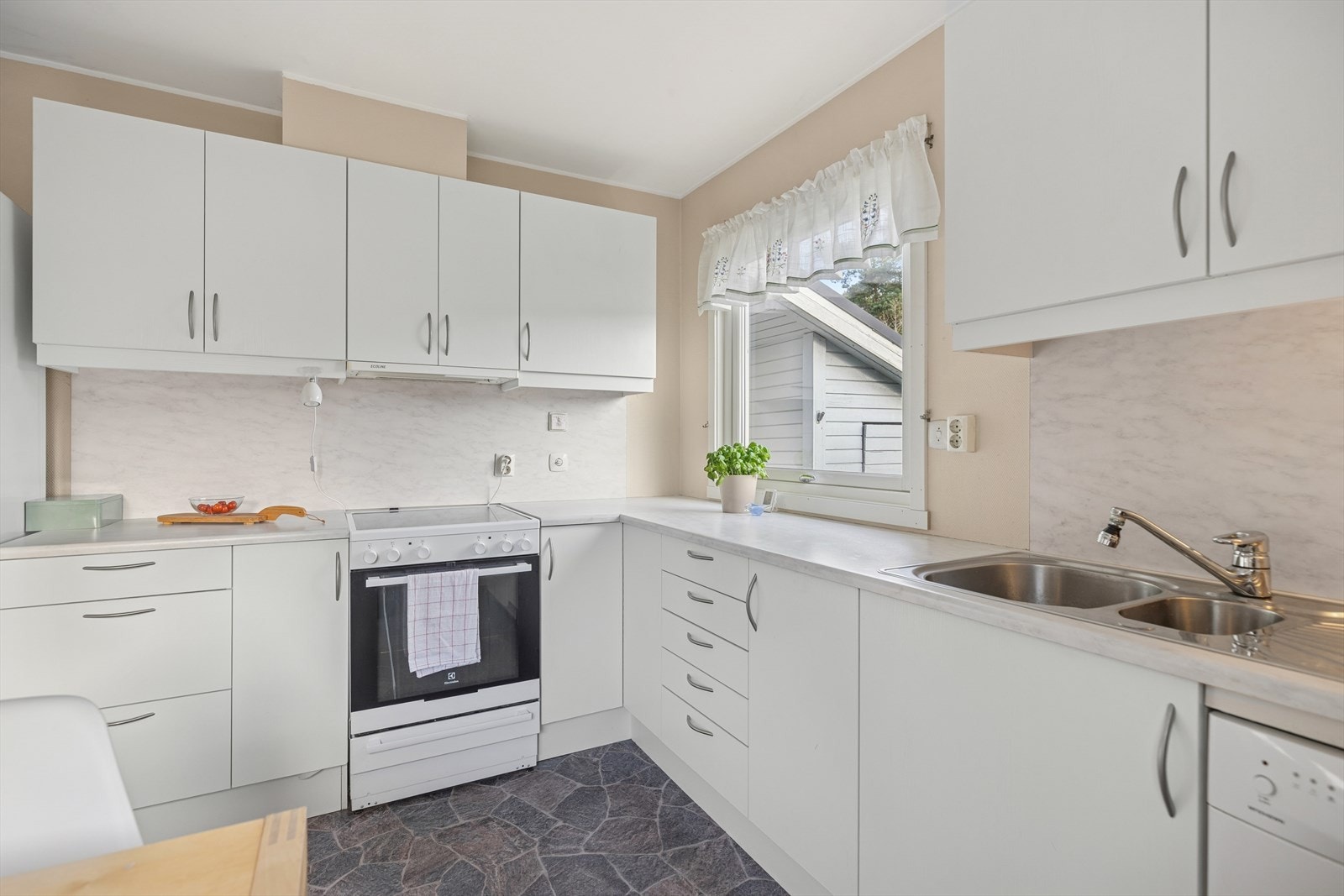 Kjøkkeninnredning med glatte fronter og laminat benkeplate med kum i rustfritt stål og blandebatteri i rustfritt stål. Galleribilde