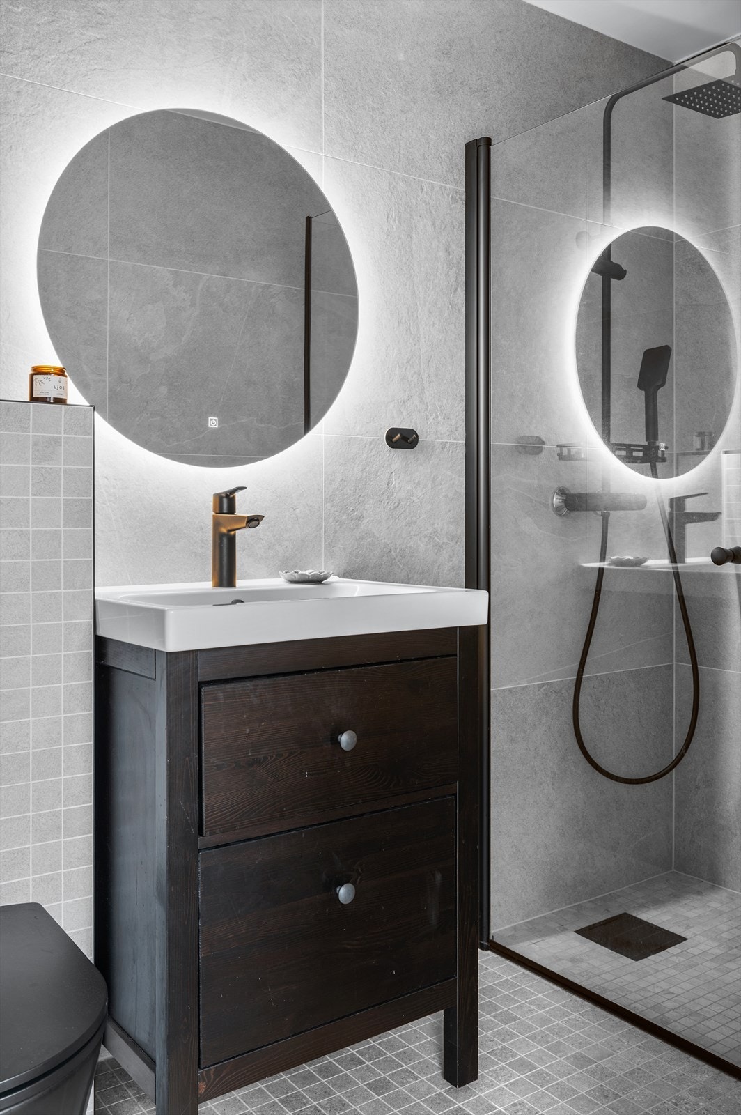 Badet gir umiddelbart en gode spafølelsen med store og små fliser, stor dusjnisje, vegghengt wc, svart armatur og baderomsmøbler. Galleribilde