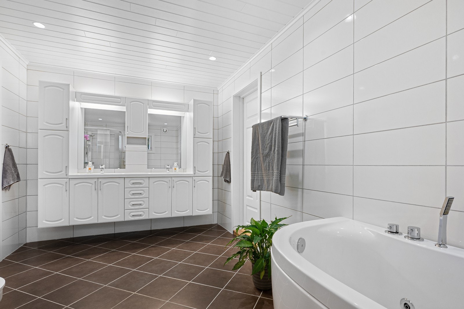 Badet i hovedetasjen har flislagte overflater i hvitt og brunt, innredning med dobbel servant, speil og godt med oppbevaringsplass. Galleribilde