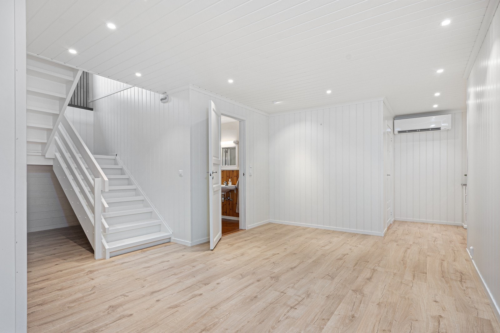 Videre kommer man inn i en lys og luftig hall som fordeler til underetasjens rom. Lyse panelvegger og moderne downlights skaper en behagelig atmosfære. Galleribilde