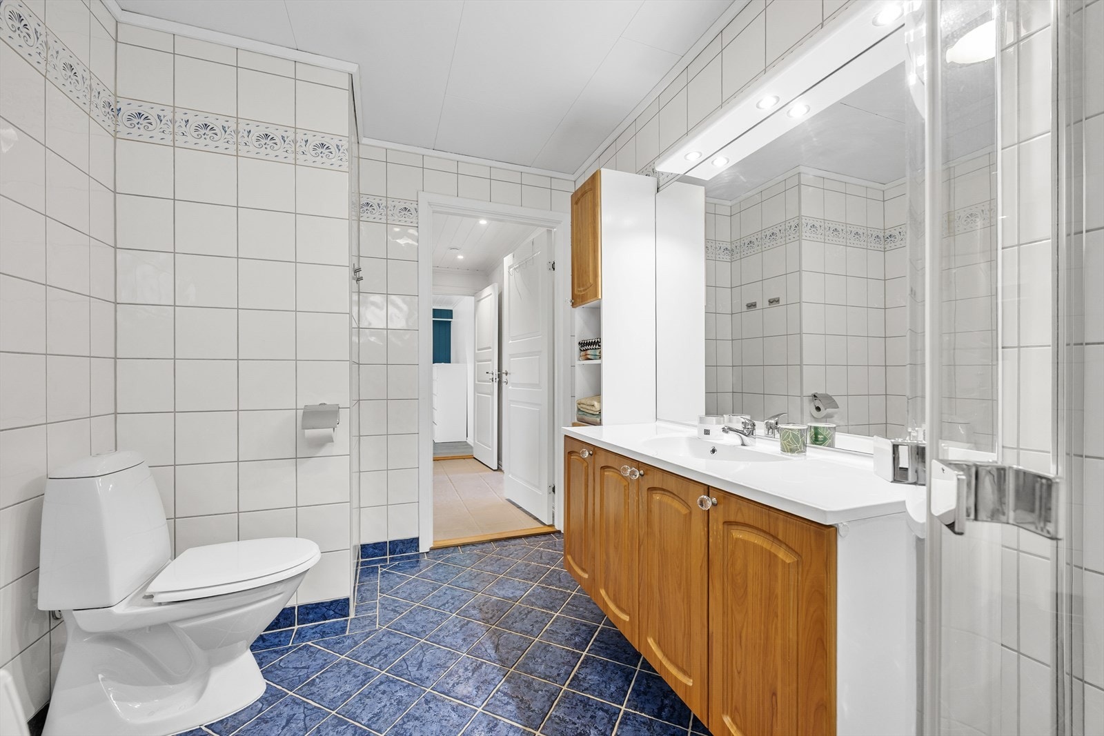 Badet i første etasje er flislagt og utstyrt med servantinnredning, toalett og dusjhjørne. Galleribilde