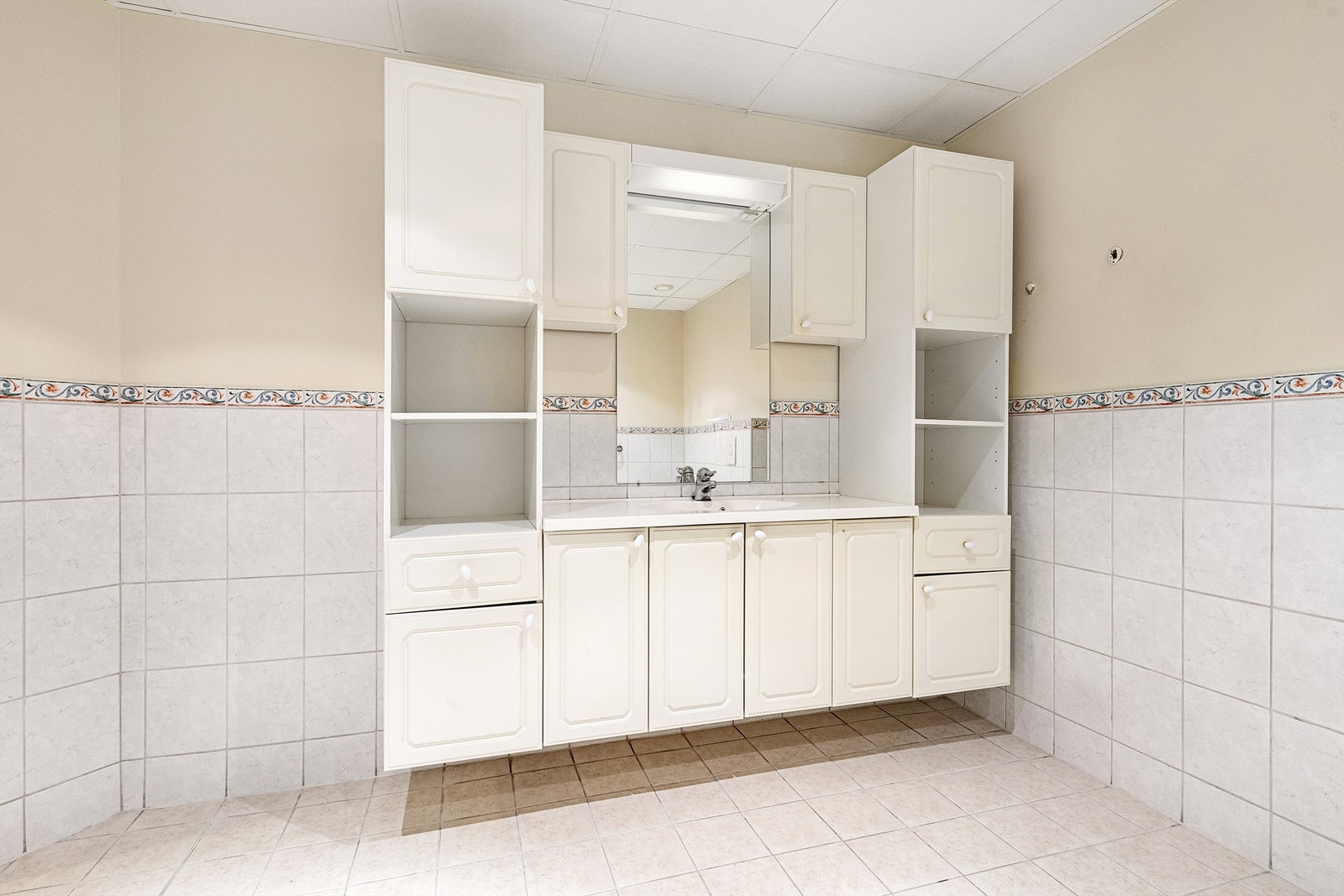 Romslig innredning på bad med ovenpåliggende servant med ett-greps armatur. Speil med overlys over servant Galleribilde