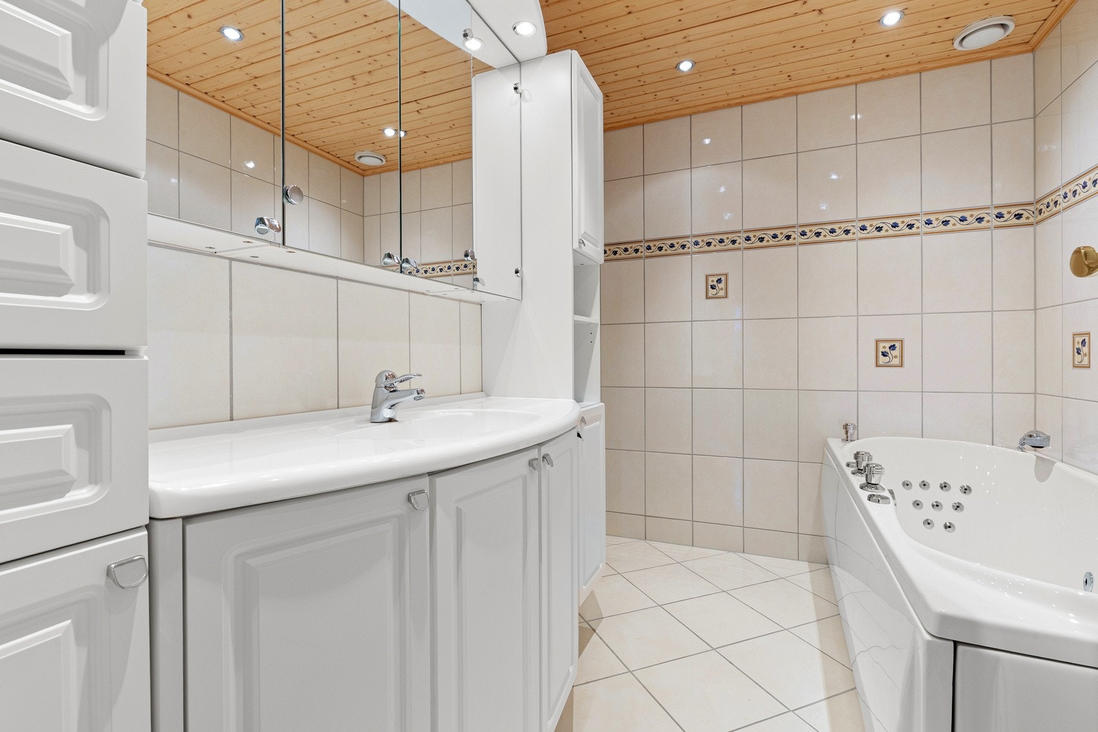 Flislagt bad med gulvvarme, dusjnisje med glassdører og boblebad. Servantinnredning med oppbevaring og speilskap med belysning. Galleribilde