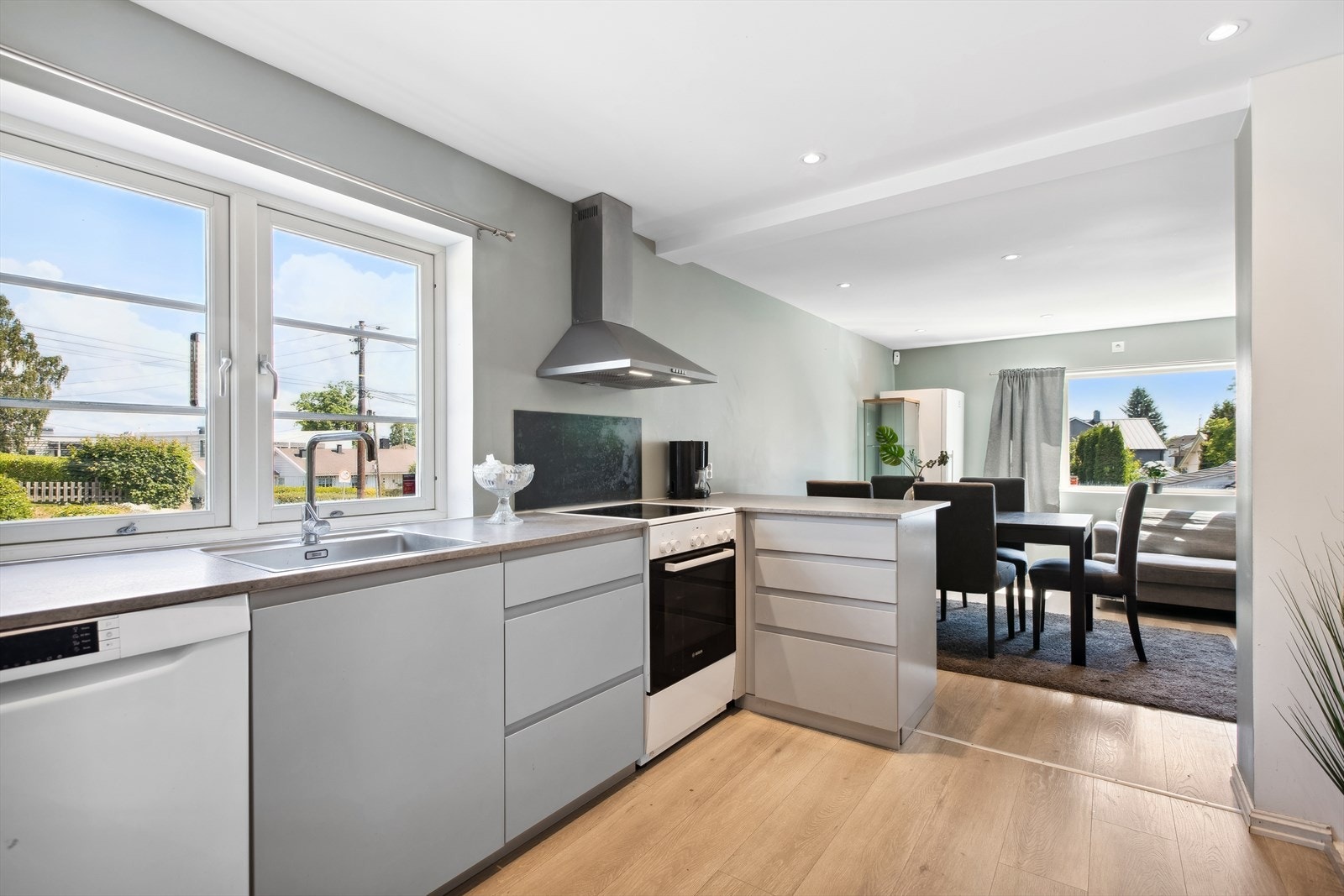 Kjøkkeninnredning fra 2020 med grå slette fronter og benkeplate i laminat. Innredningen er åpen mot stuedelen og det er godt med benkeplass Galleribilde