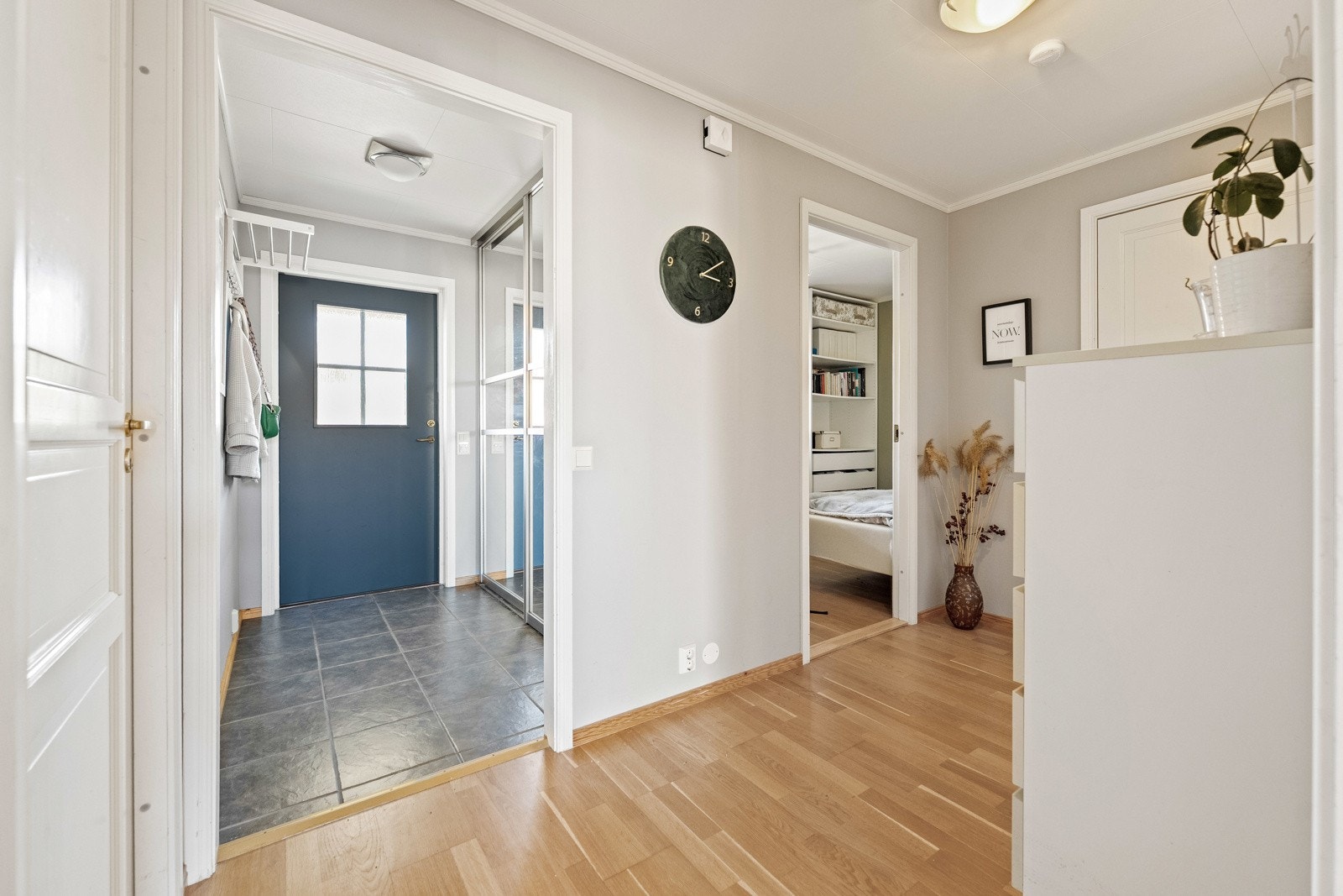 Entreen har mørkegrå gulvfliser, gråmalte vegger og en større skyvedørsgarderobe med speildører. Galleribilde