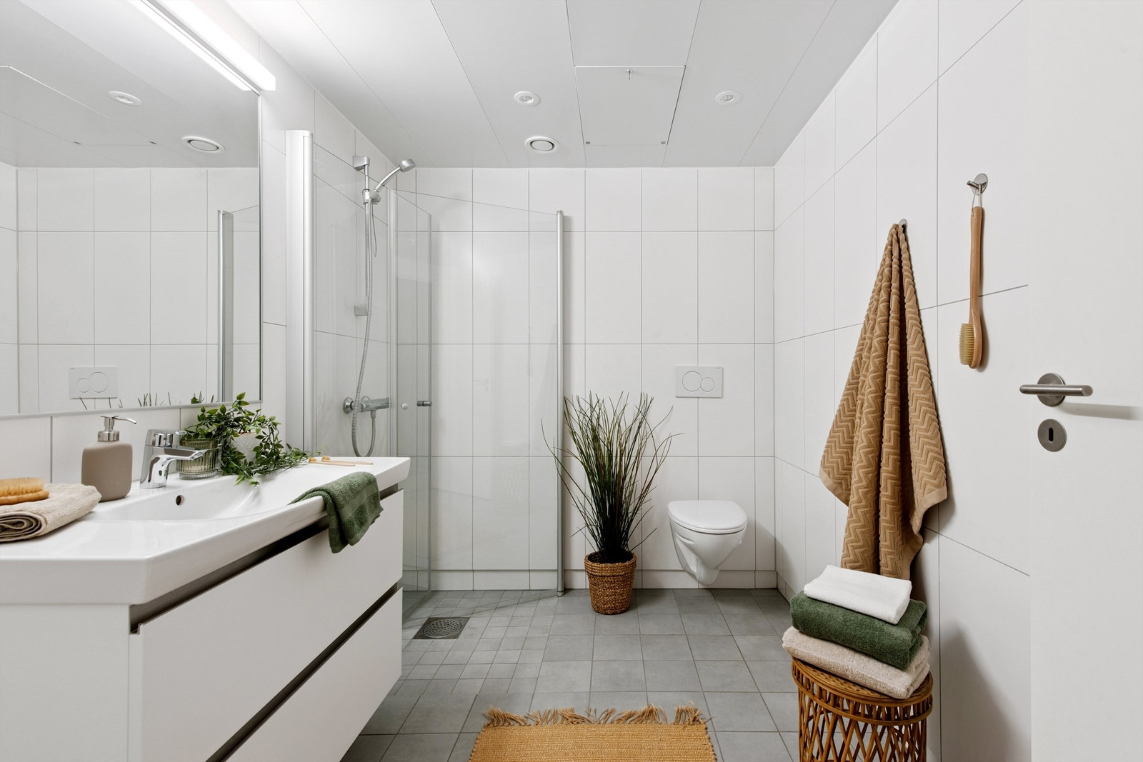 Romslig bad med lyse overflater og opplegg for vaskemaskin. Galleribilde