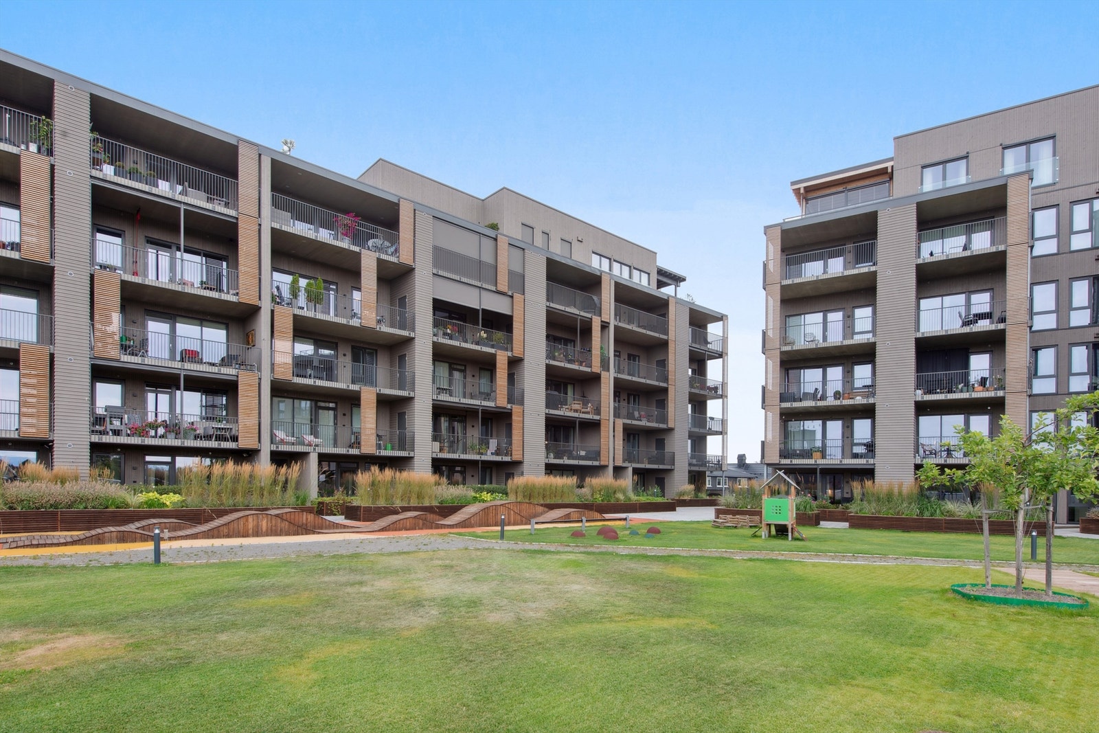 Atriet inne i sameiet er meget pent opparbeidet med plen, blomsterkasser, betongheller og lekeapparater. Galleribilde