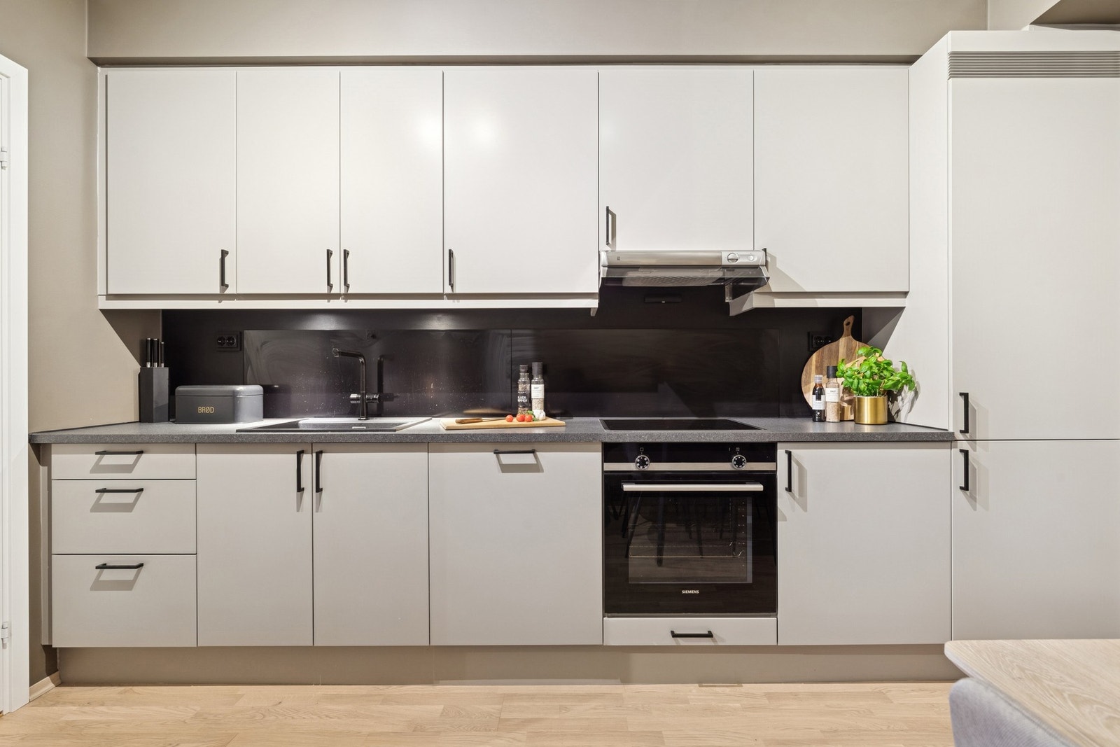 Kjøkkeninnredning med fronter i glatt utførelse, laminat benkeplate. Integrert koketopp, komfyr, oppvaskmaskin og kjøl/frys. Galleribilde