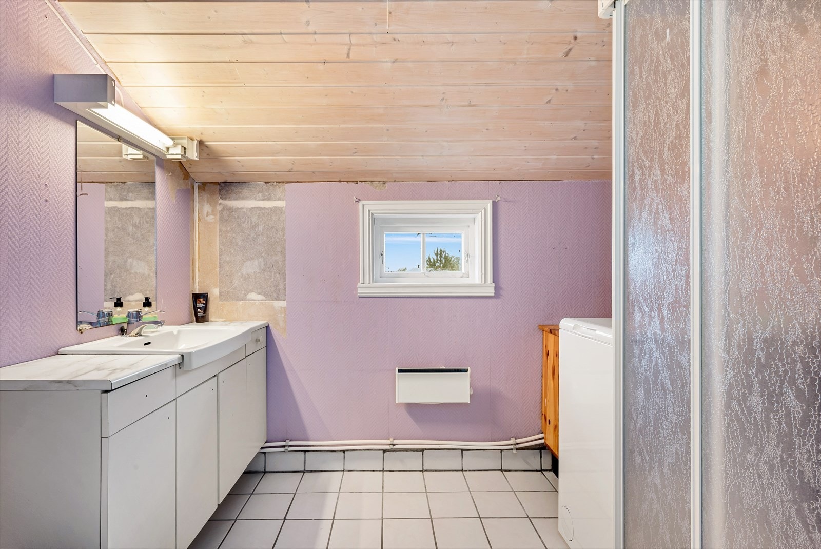 Badet er innredet med benkeplate i laminat, nedfelt vask, speil med lys, toalett, dusjkabinett og opplegg for vaskemaskin. Galleribilde
