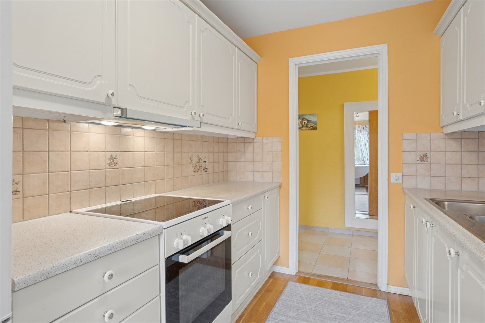 Det er flislagt mellom benkeplaten og overskapene. Galleribilde