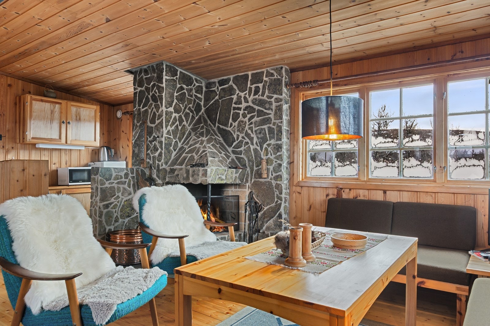 Peisen og brannmuren, og som er forblendet med naturstein, fungerer som en fin romdeler mellom stue og kjøkken. Galleribilde