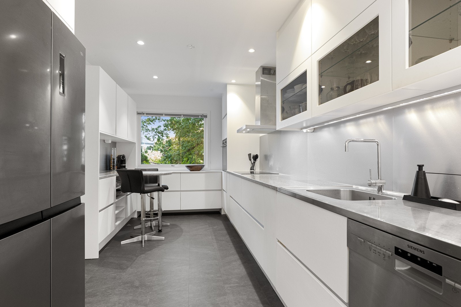 Lys og delikat kjøkken fra 2019 godt utstyrt med benke- og skapplass, samt integrerte hvitevarer som stekeovn, induksjonstopp og oppvaskmaskin Galleribilde