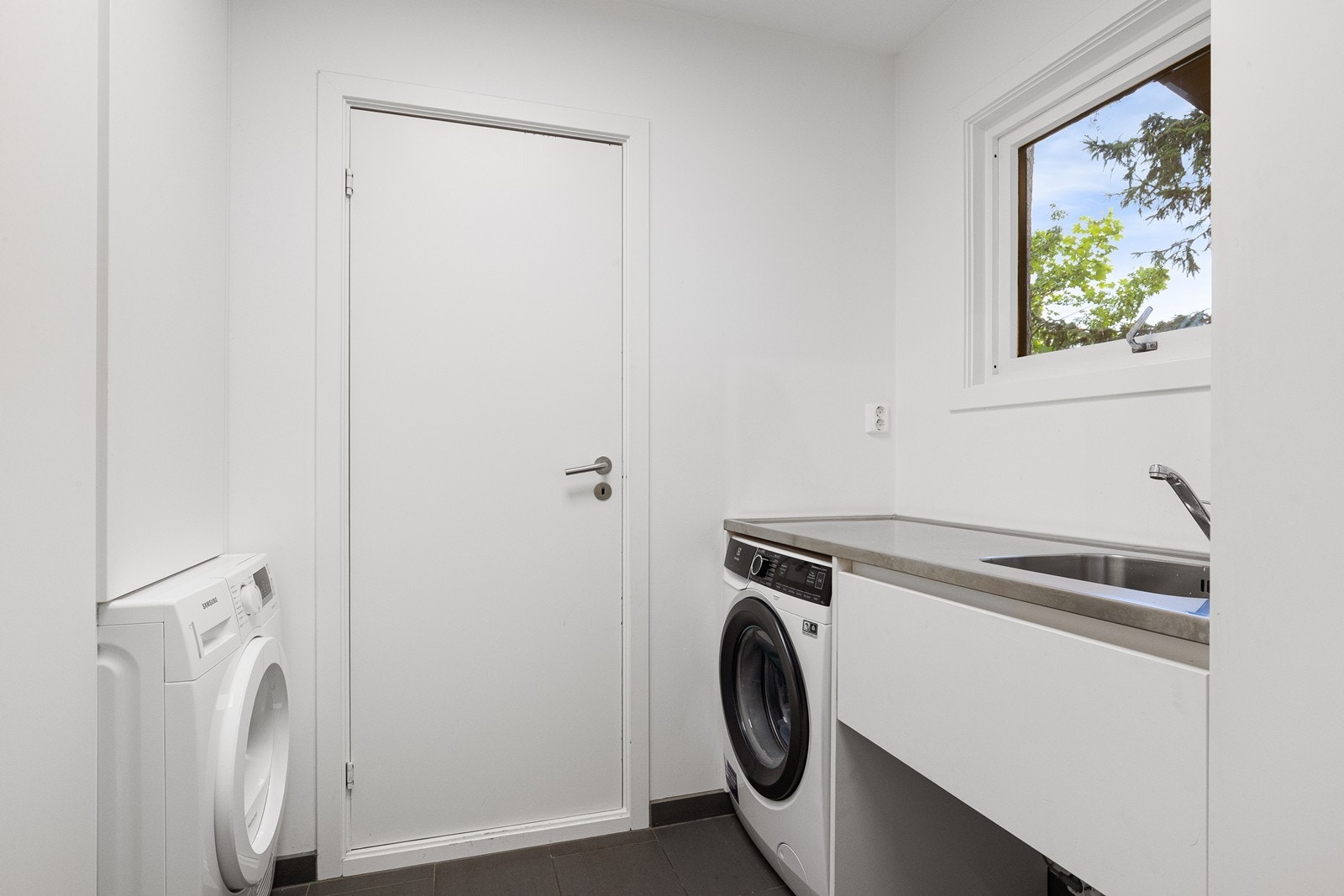 Vaskerom oppgradert i 2017 med malte flater på vegg, og malte flater i tak og fliser på gulv med gulvvarme. Vaskerommet ligger praktisk plassert innenfor entreen og med adkomst videre til kjøkkenet Galleribilde