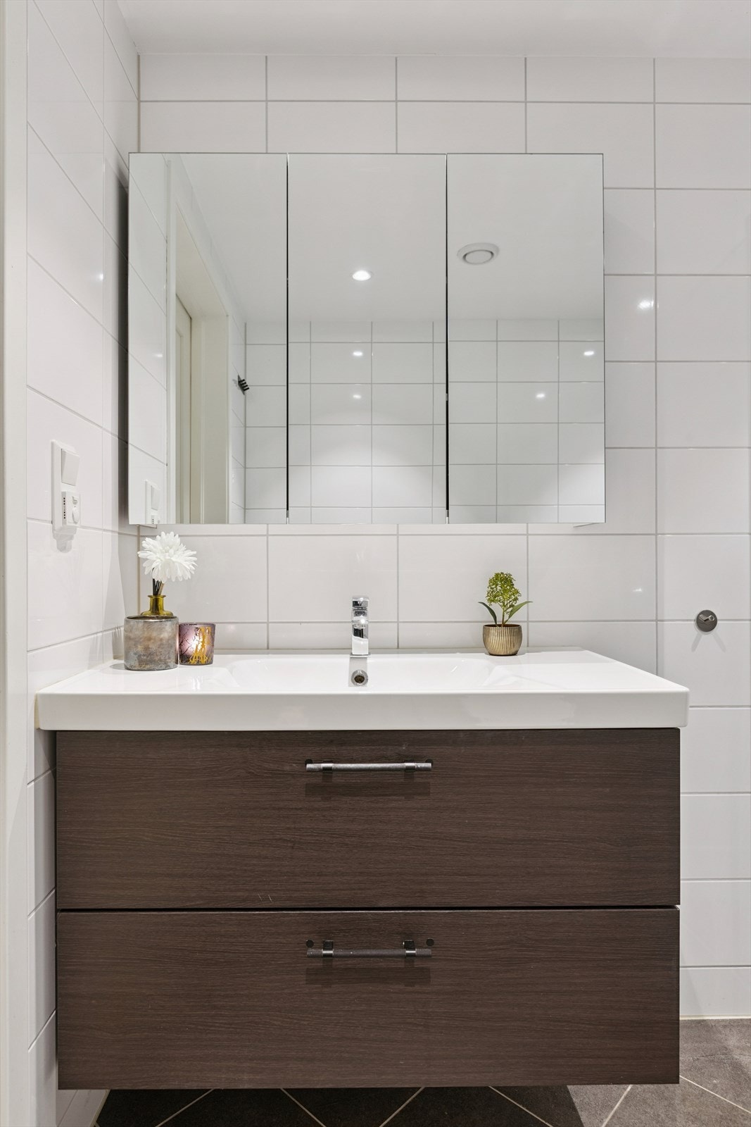 Badet er utstyrt med gulvvarme dusjhjørne, innfellbare dusjdører, mekanisk avtrekk, servant, servantskap og veggmontert wc. Galleribilde