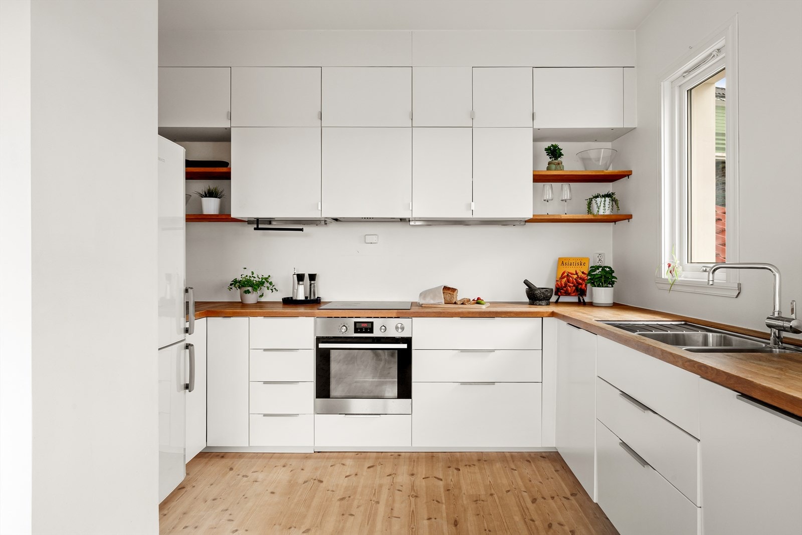 Kjøkken med heltré benkeplate og integrerte hvitevarer som induksjon platetopp, steikeovn og oppvaskmaskin. Galleribilde