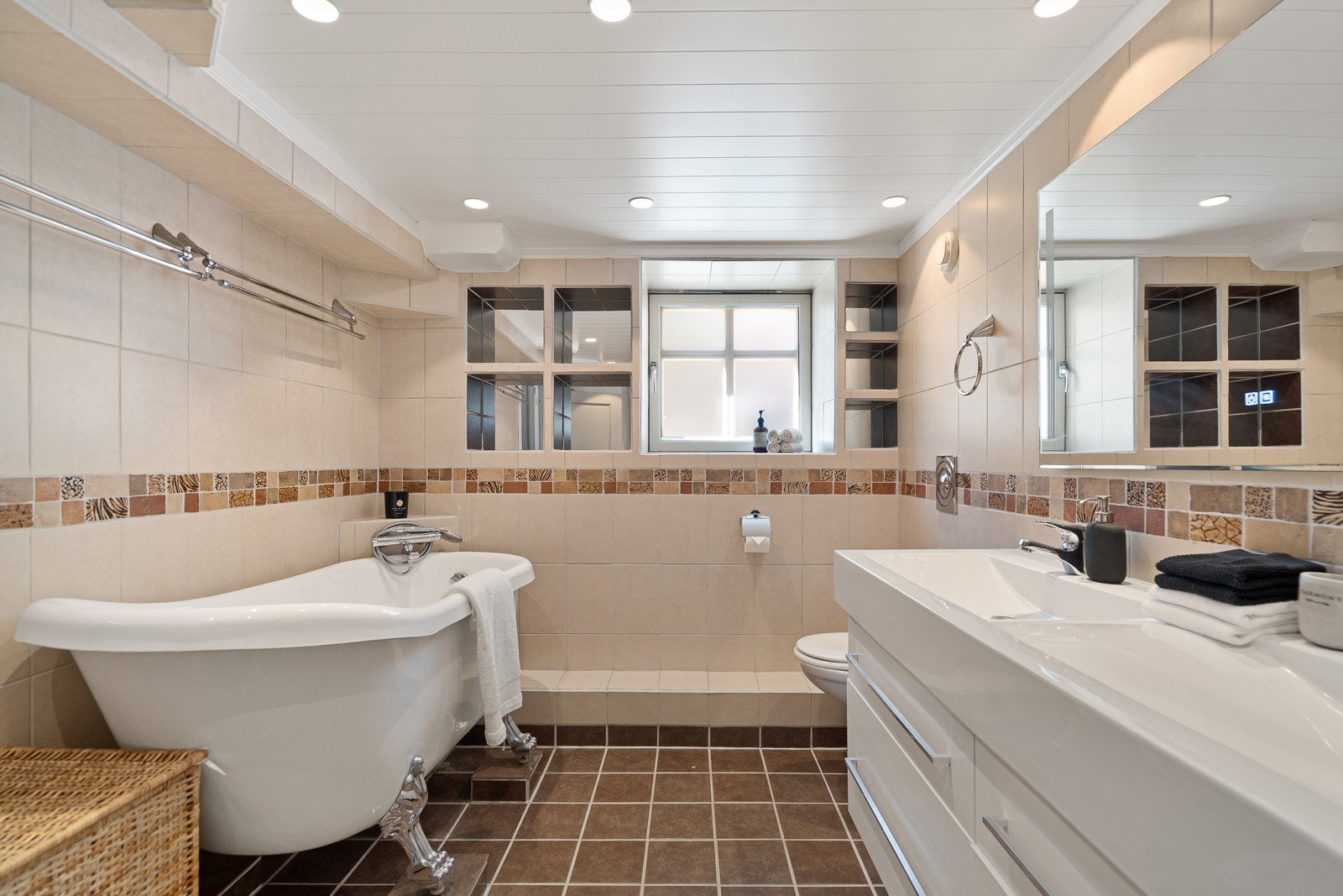 Romslig bad med både badekar, doble servanter og opplegg for vaskemaskin Galleribilde