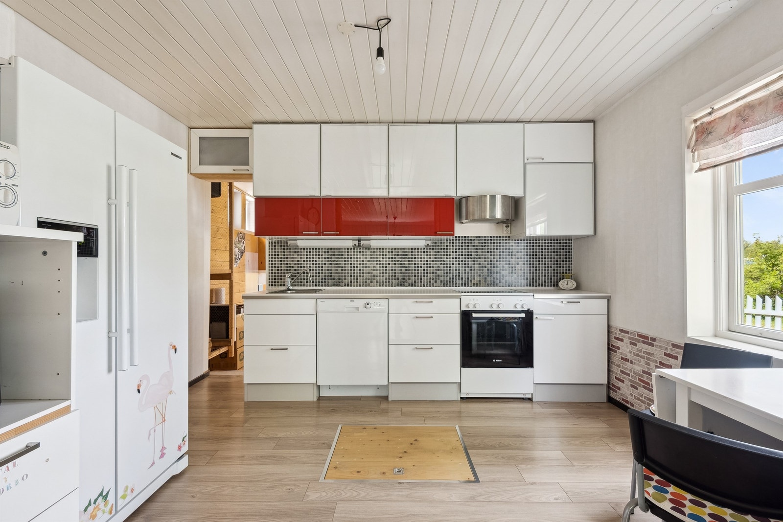 Kjøkken fra Ikea med slette fronter, mosaikkfliser og plass til frittstående hvitevarer. Galleribilde